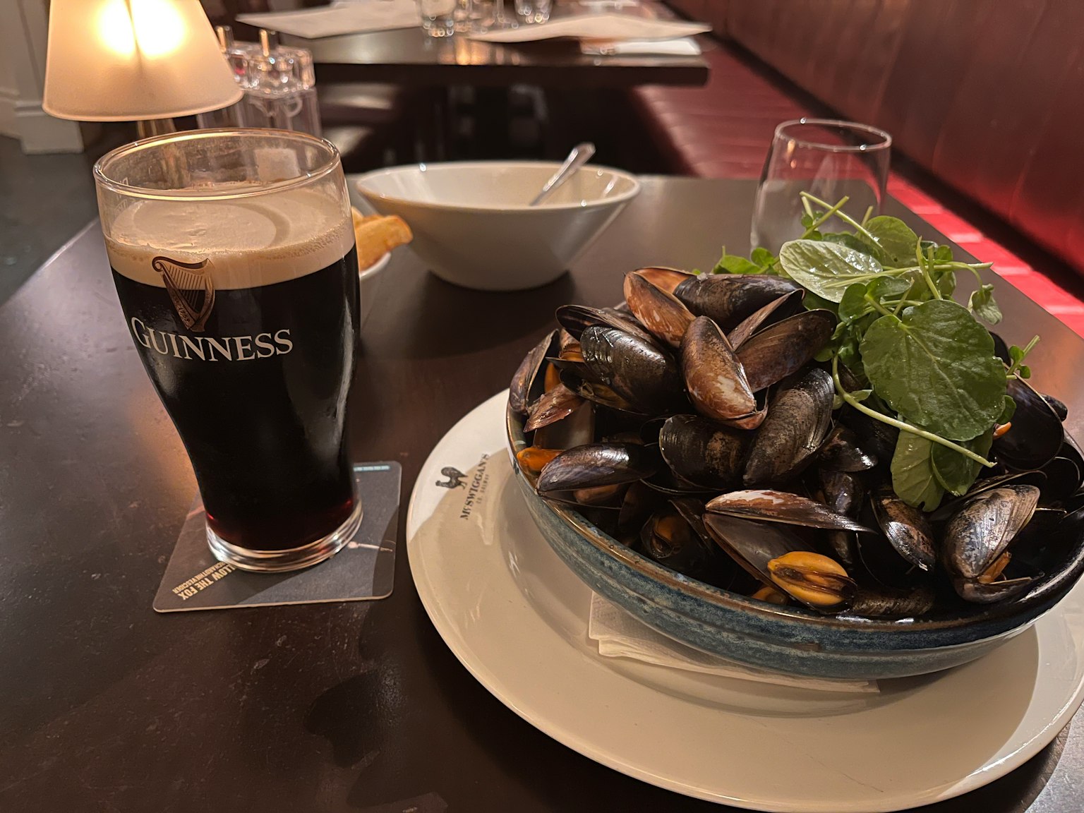 Table setting with a bowl of mussels and a pint of Guinness