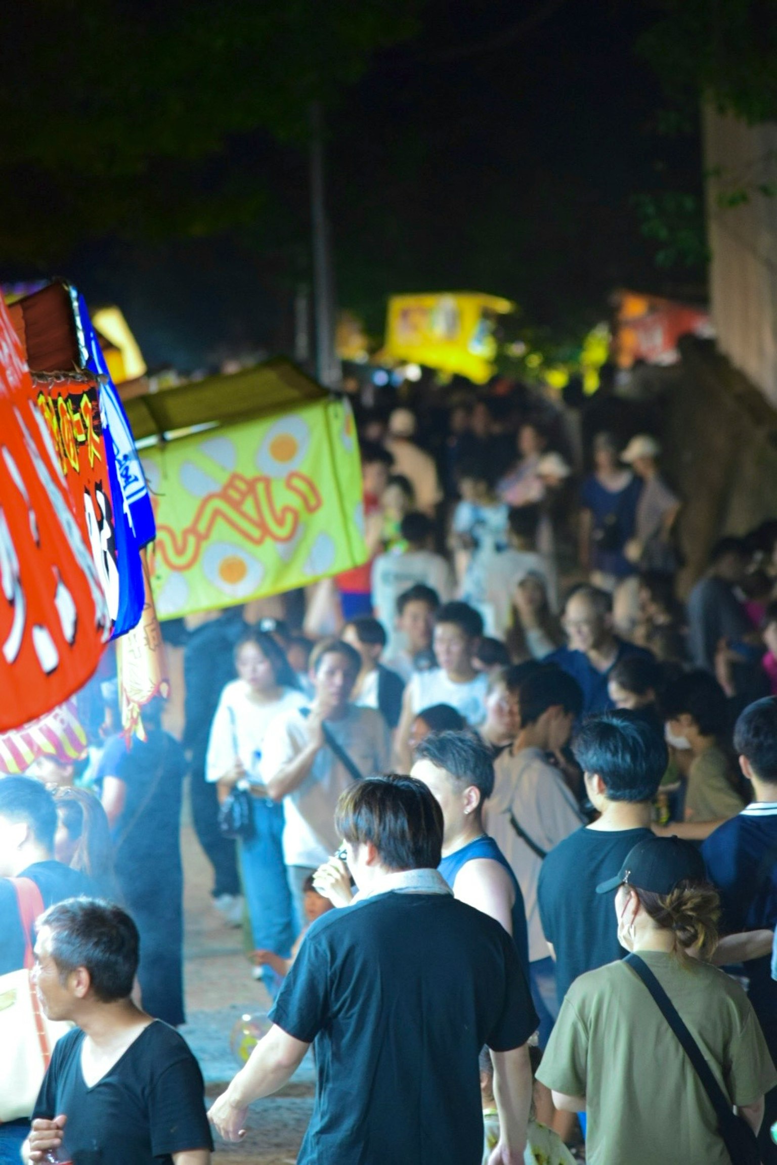 Menschenmenge auf einer lebhaften Straße mit Essensständen bei Nacht
