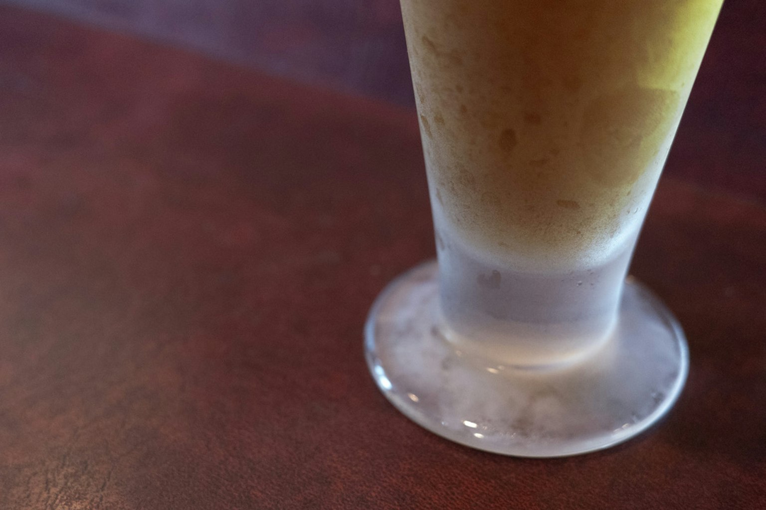 木桌上透明玻璃杯中飲料的局部視圖