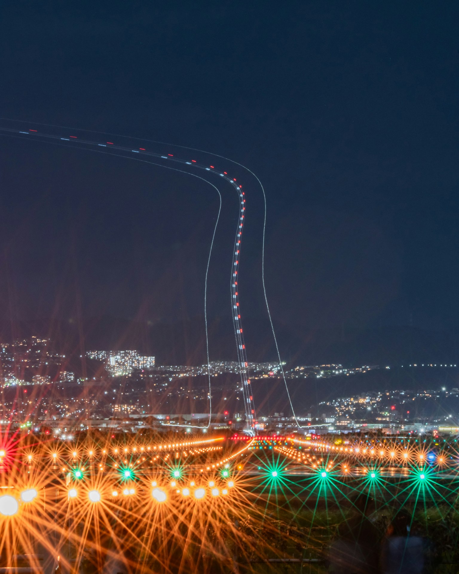 夜景の中に光の軌跡が見える空港の滑走路の写真