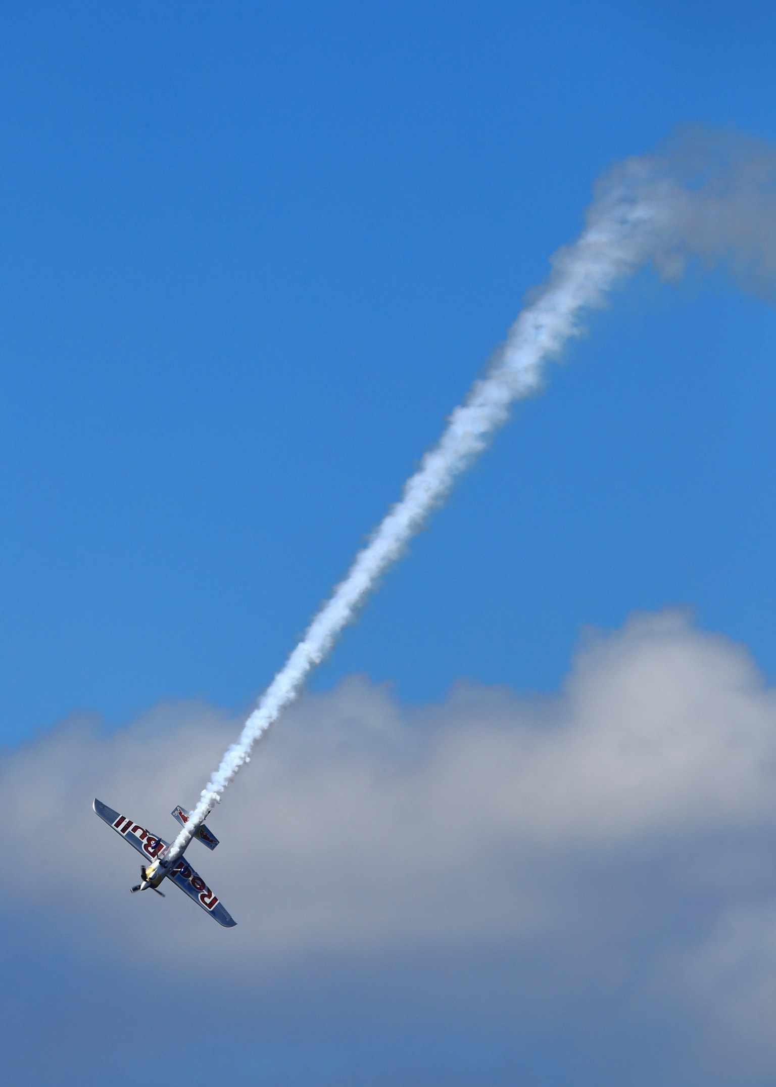 青空を背景に煙を出しながら旋回する飛行機