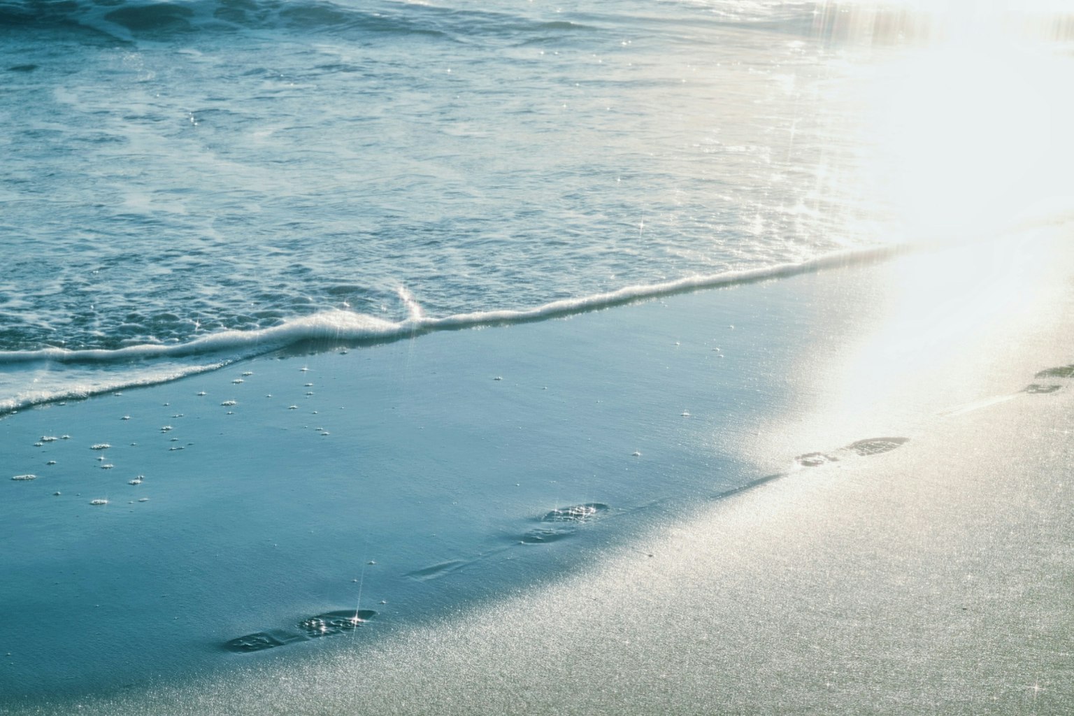 Pemandangan pantai yang tenang dengan ombak lembut mengalir ke tepi
