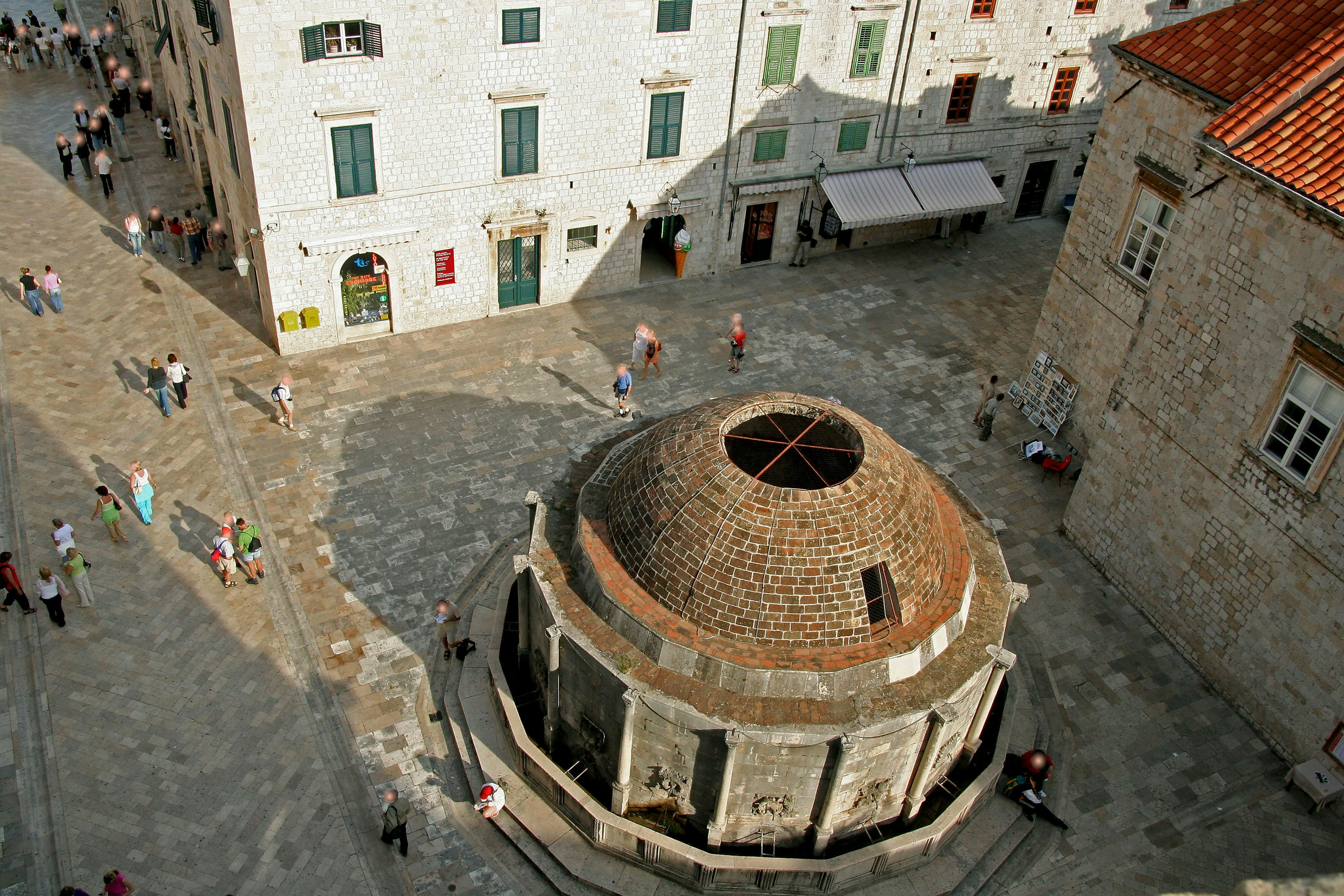 Overhead view of a circular stone building and people in a courtyard square