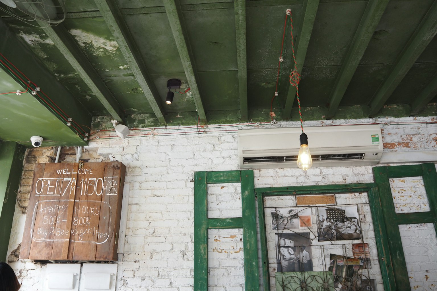 Interior de una cafetería con techo verde y paredes de ladrillo blanco