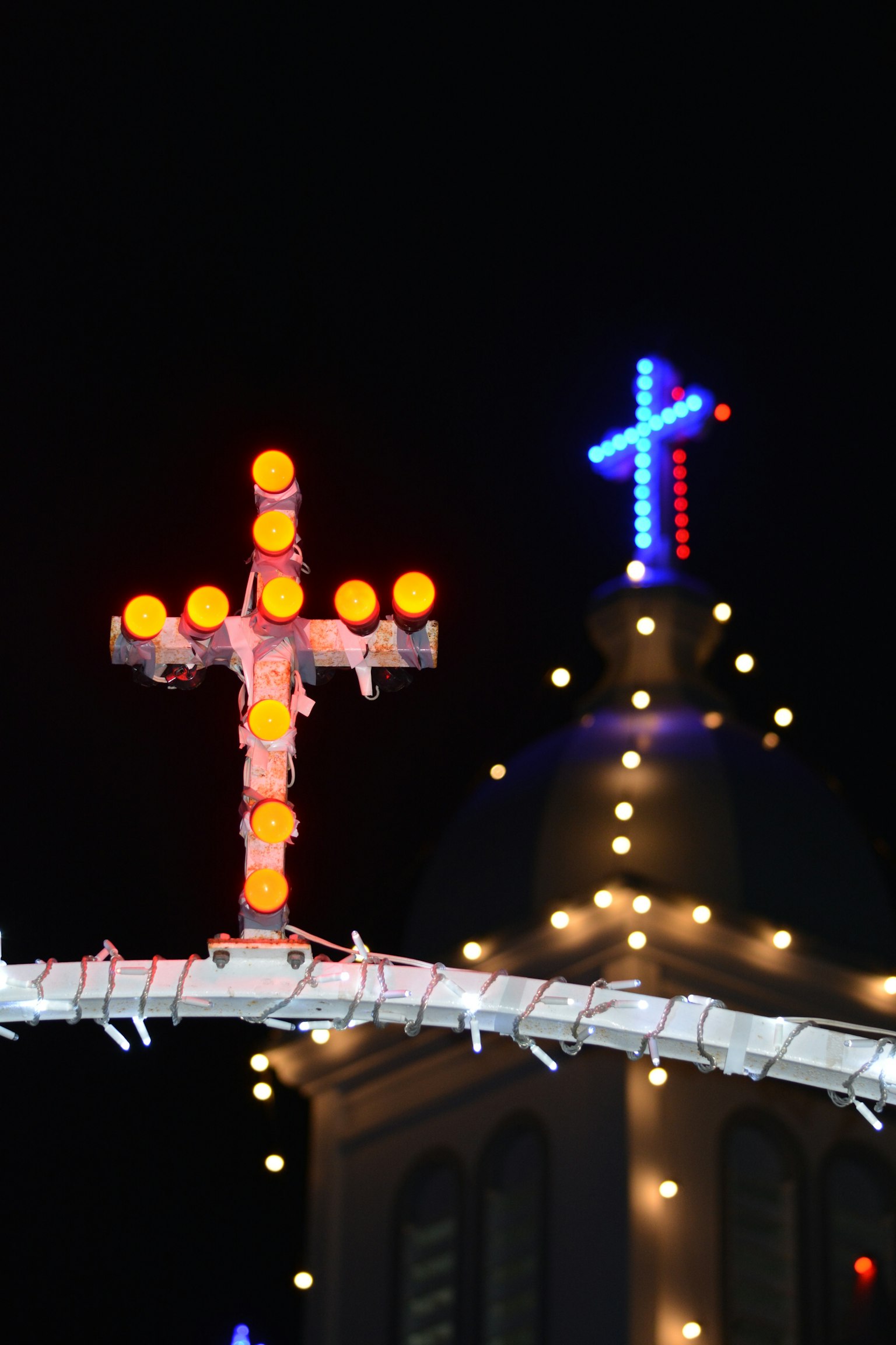 Beleuchtete Kreuze und Kirchturm bei Nacht