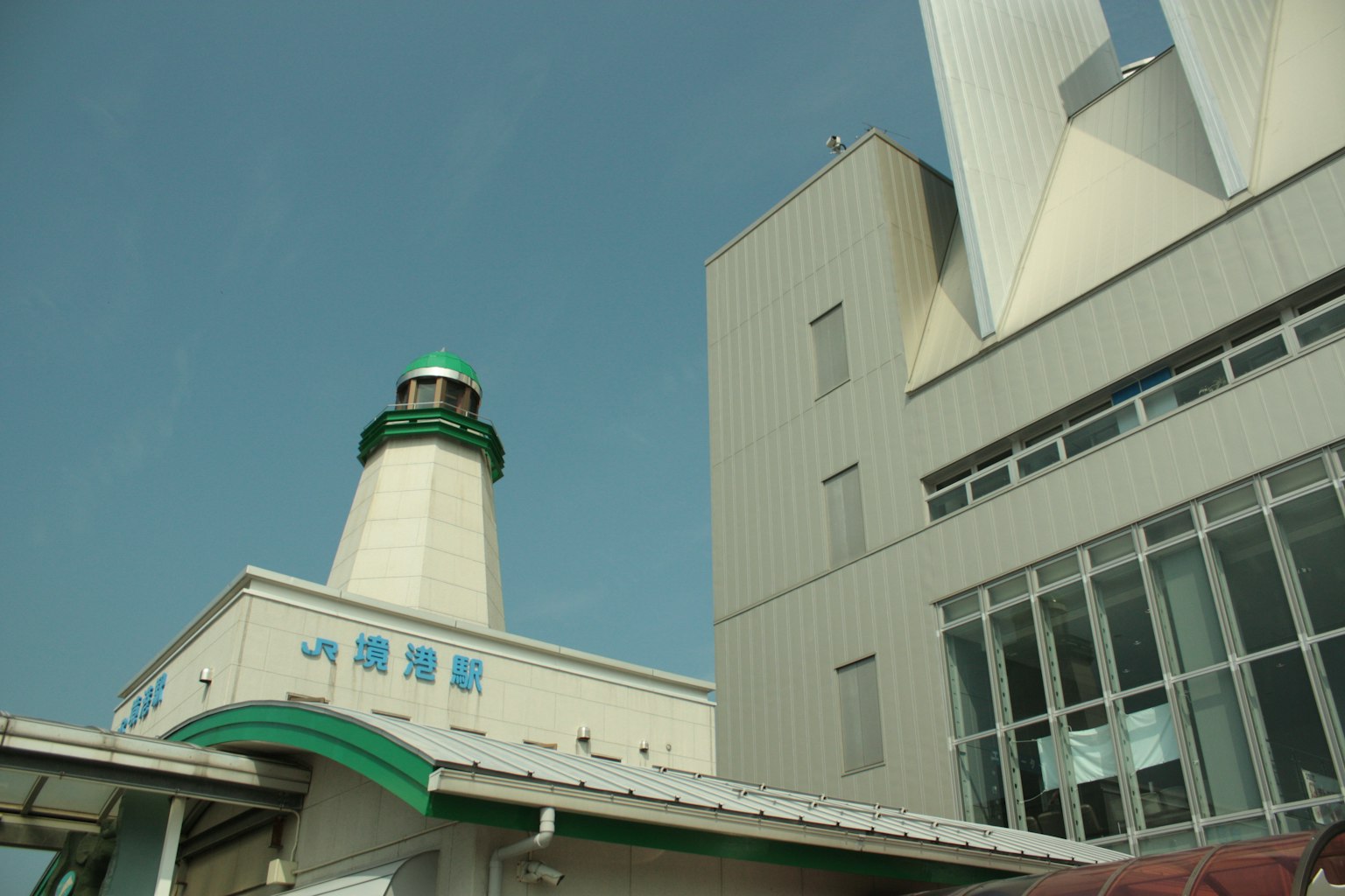 Mercusuar di sebelah gedung modern di bawah langit biru yang cerah