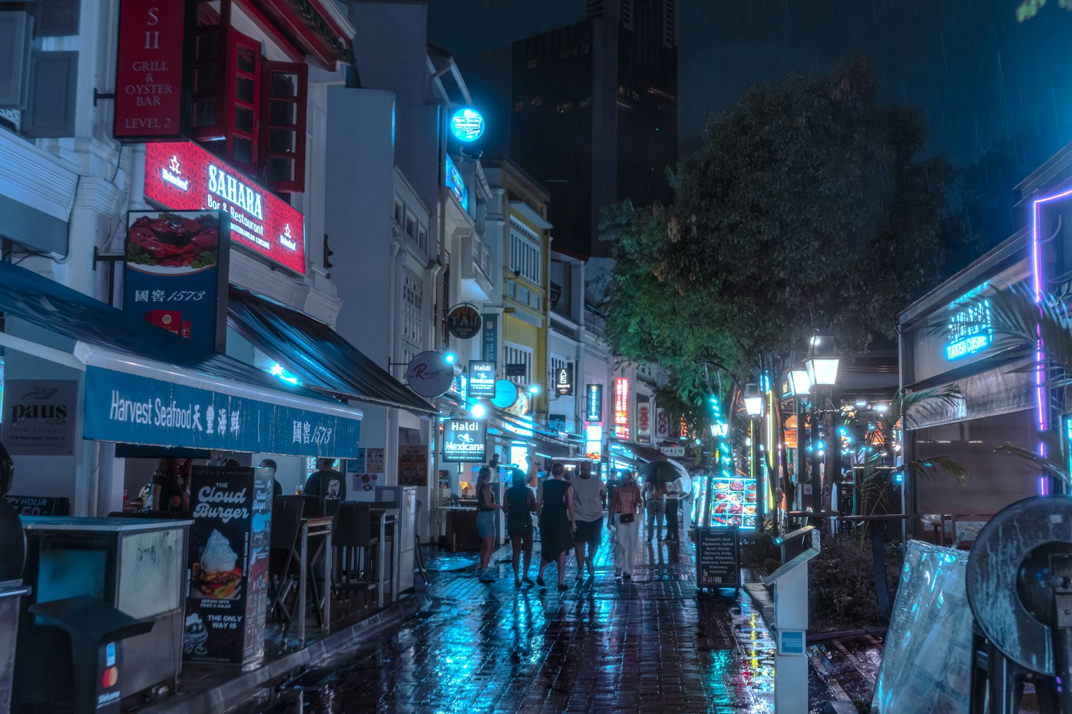 ฉากถนนยามค่ำคืนที่มีไฟนีออนสว่างและทางเท้าที่เปียก