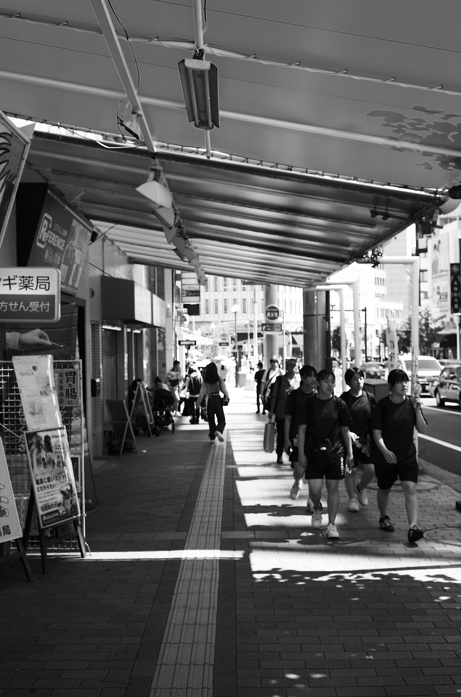 人們在黑白街景中走動，旁邊有商店招牌