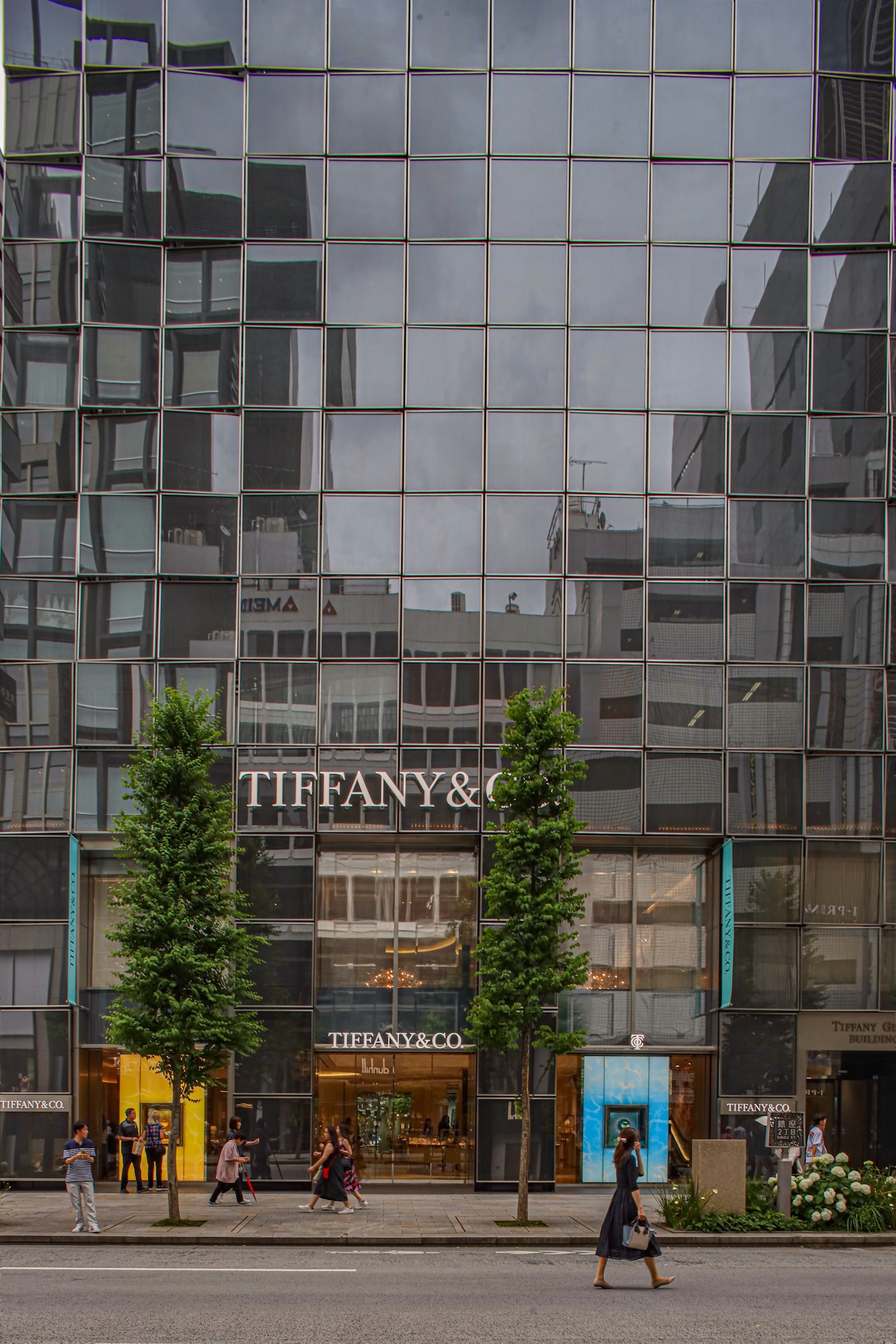 Fasad bangunan modern menampilkan toko Tiffany & Co orang-orang berjalan