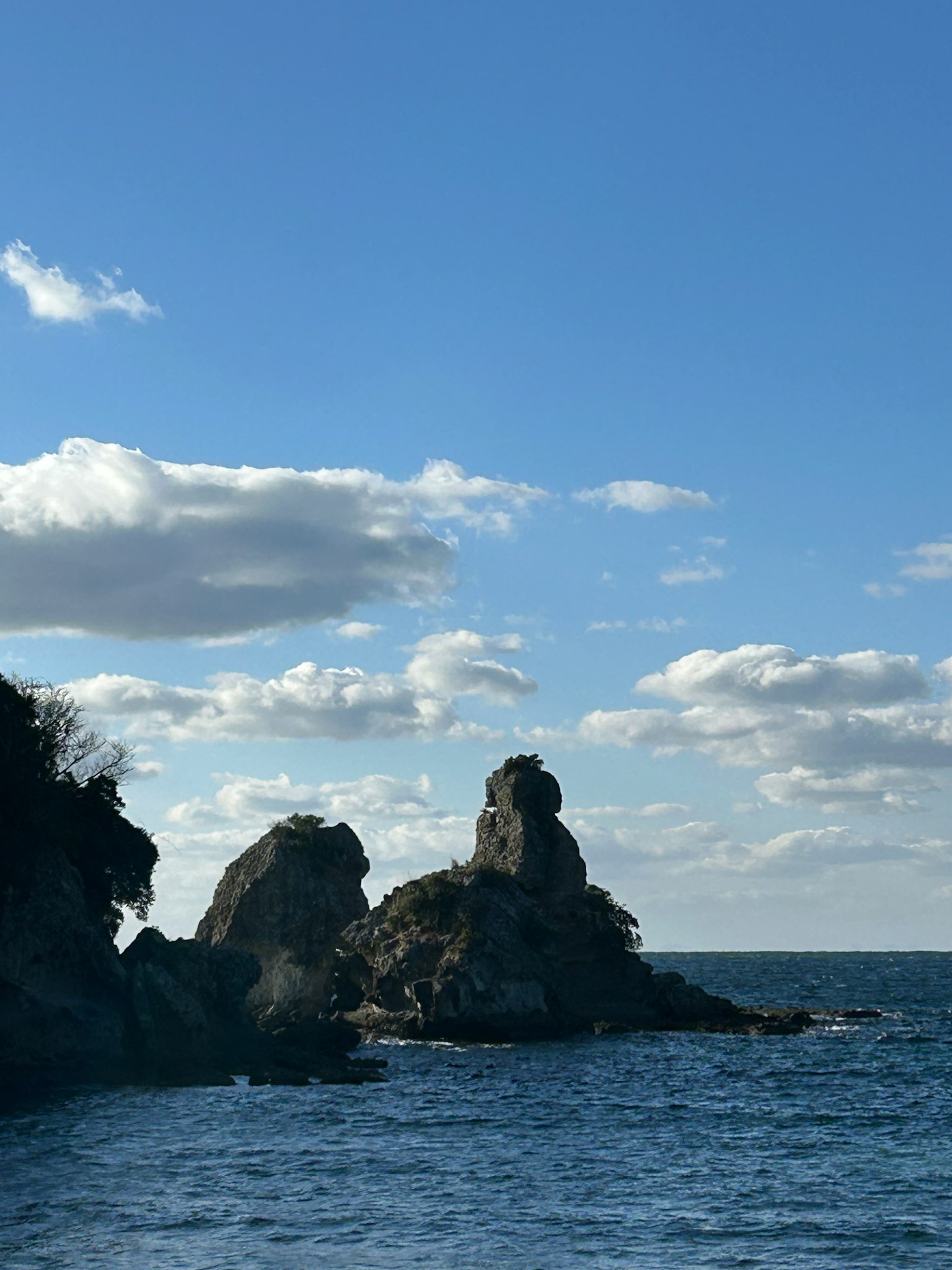 Vista escénica de la costa rocosa bajo un cielo azul y nubes