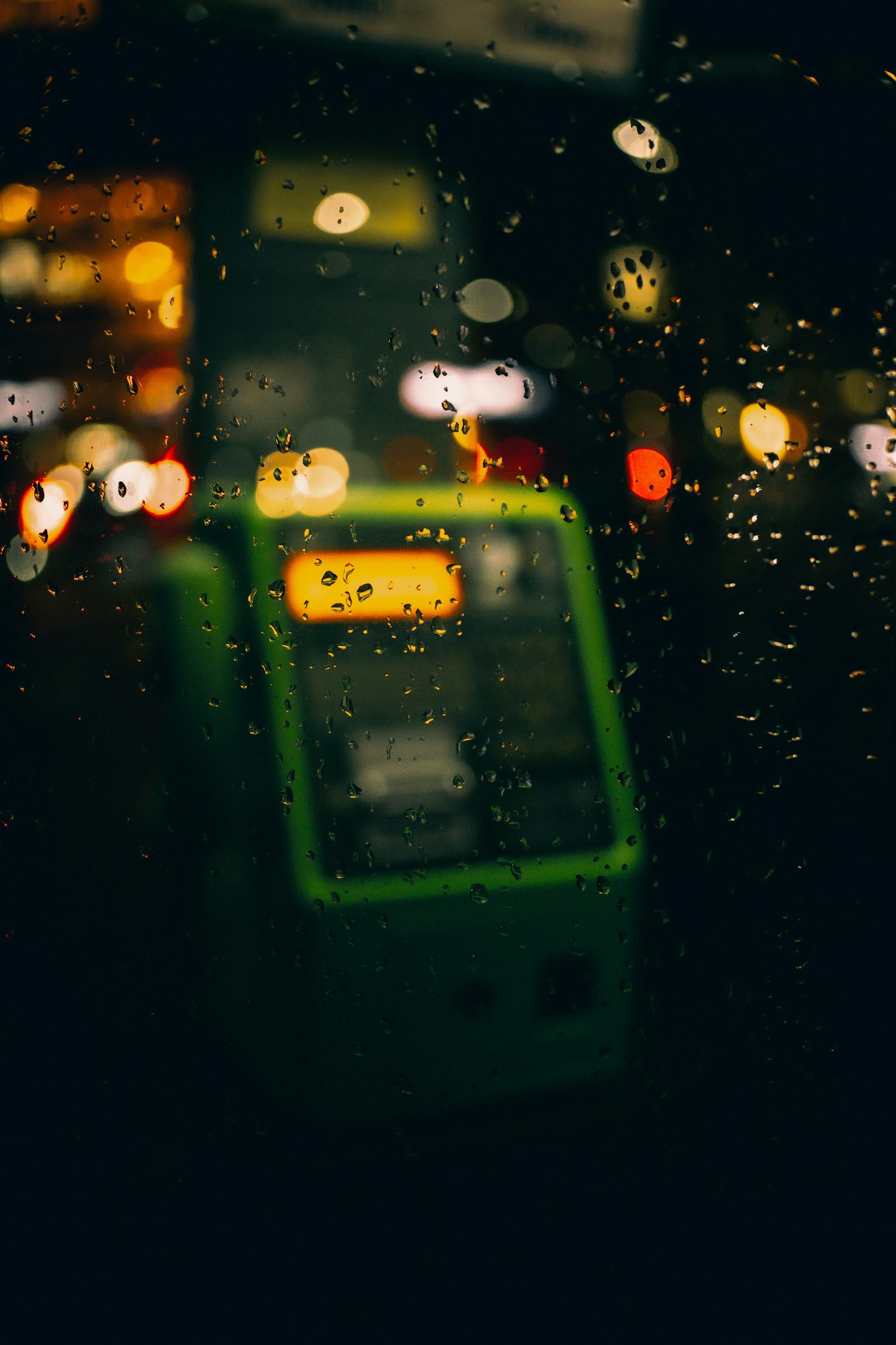 Máy bán hàng tự động màu xanh bị ướt bởi mưa với ánh sáng nền mờ