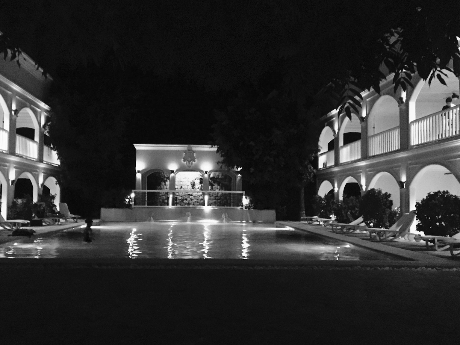 Schwarz-Weiß-Bild eines Resortbereichs mit Pool bei Nacht