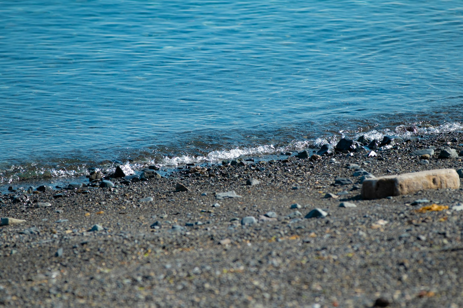 Orilla con olas suaves y guijarros junto al agua