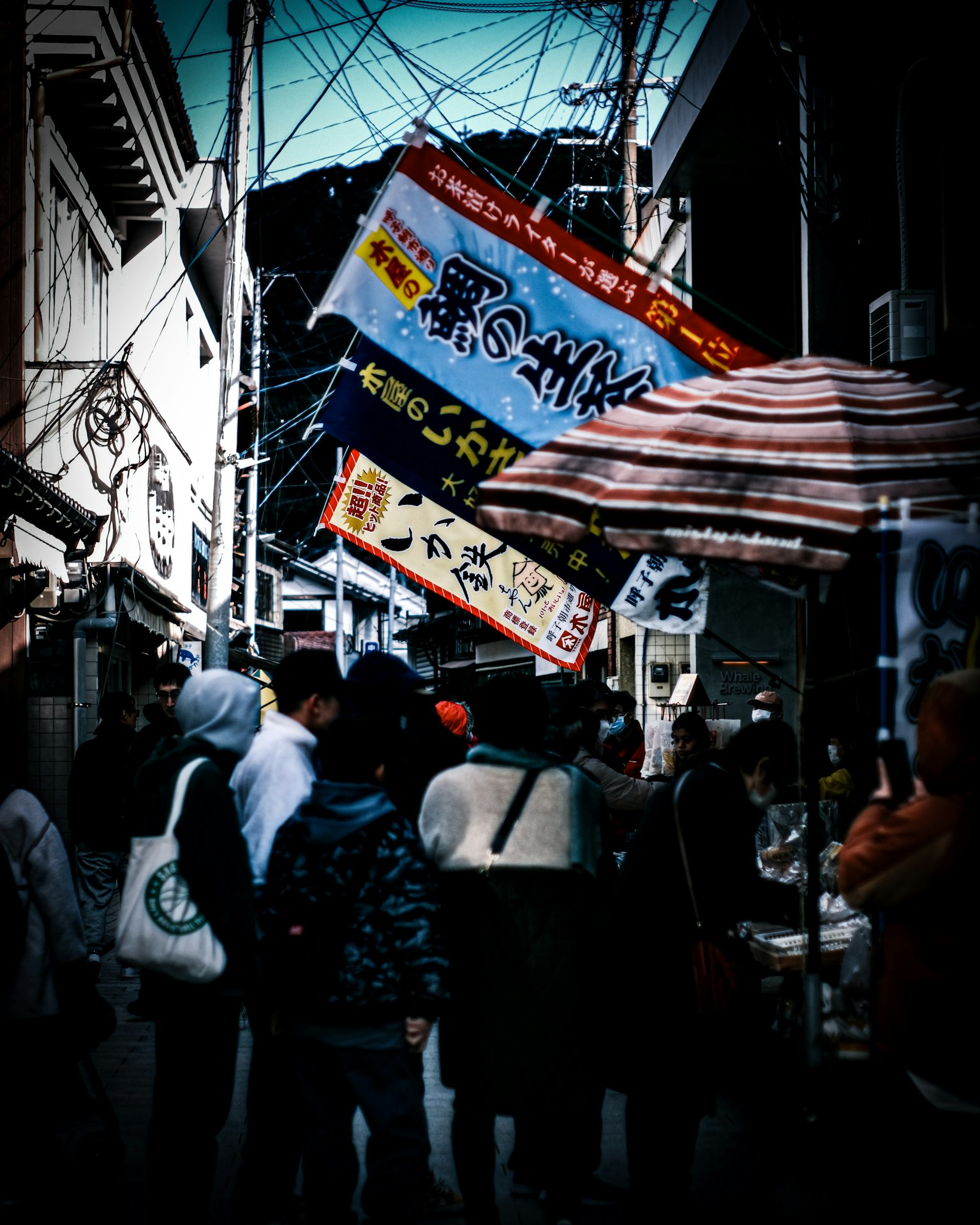 Crowded street market with people and colorful banners hanging