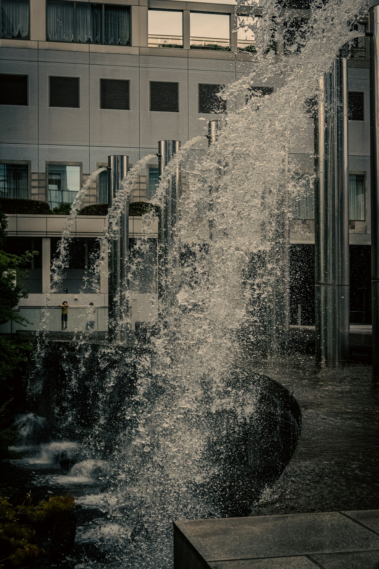 Cascade d'eau devant un bâtiment moderne avec des piliers métalliques