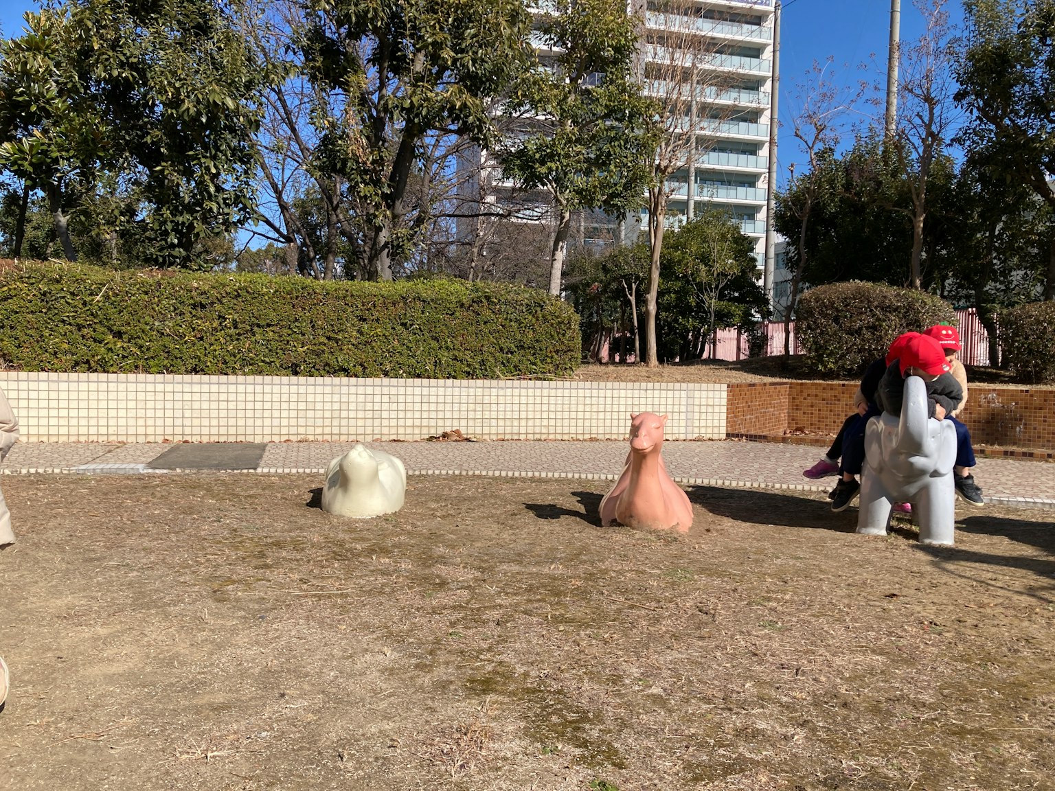 Animal-shaped sculptures in a park playground with a high-rise building in the background