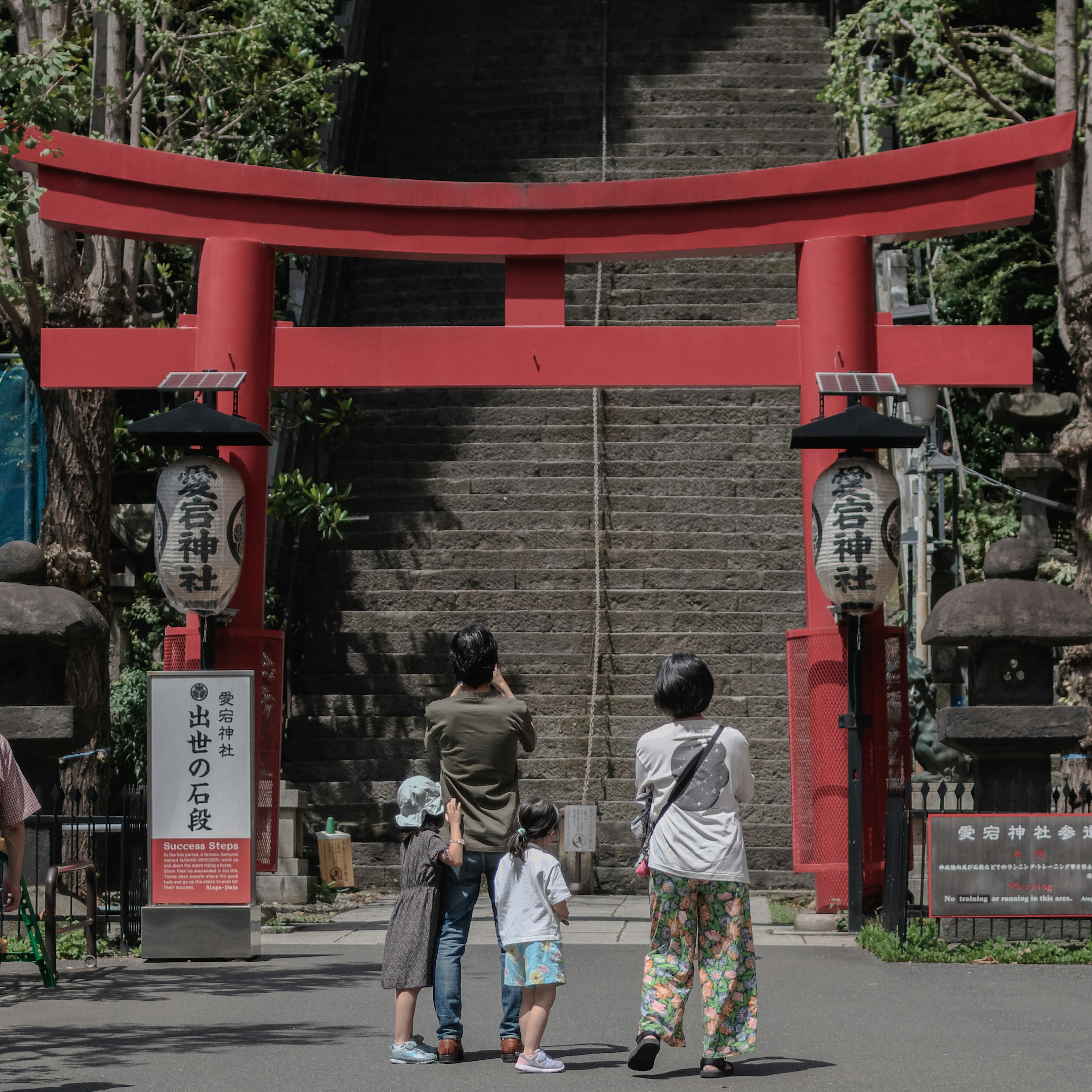 愛宕神社の朱塗りの鳥居と参拝者が石段の前にいる風景