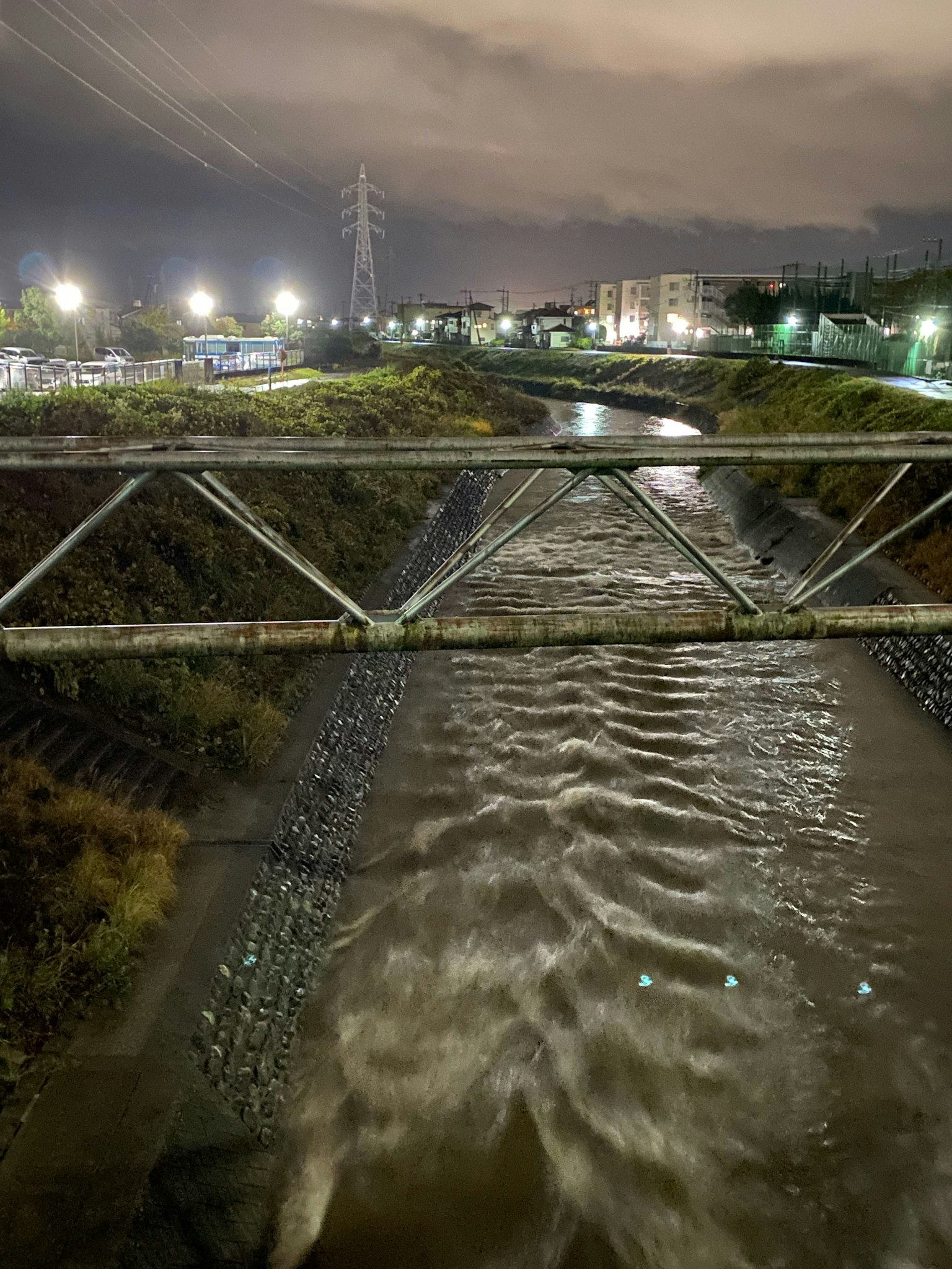 Metal bridge over a river at night with surrounding streetlights