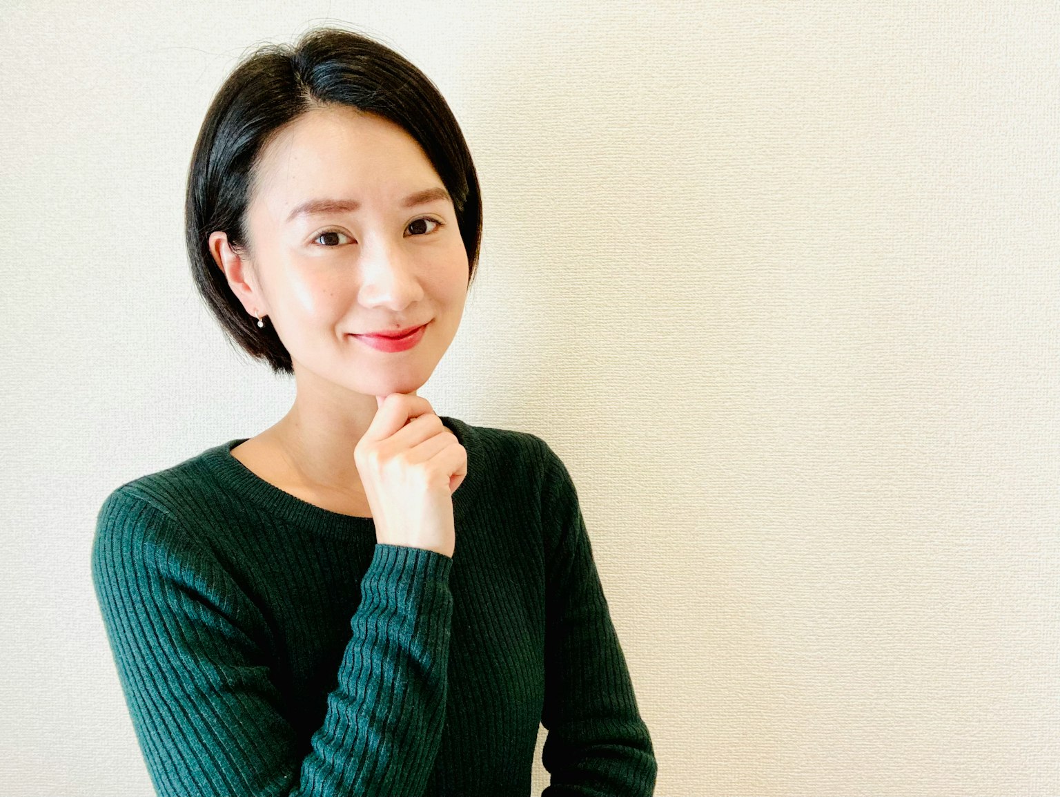 A woman smiling thoughtfully with her hand on her chin