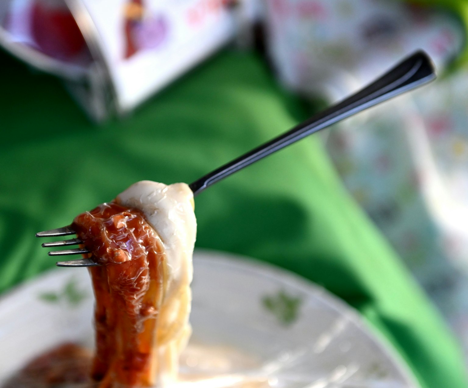 Kedekatan makanan yang diangkat dengan garpu dengan saus krim di atas piring