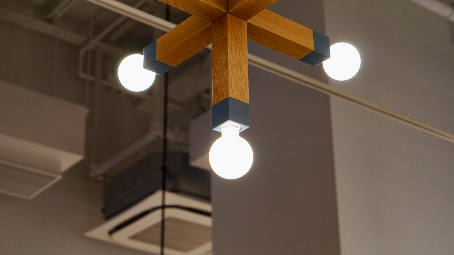 Un lampadario in legno con quattro lampadine bianche