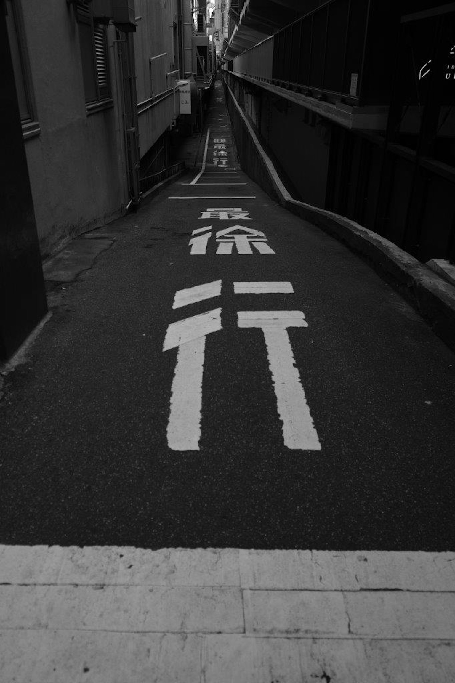 Sendero pavimentado estrecho con marcas de tráfico blancas en blanco y negro