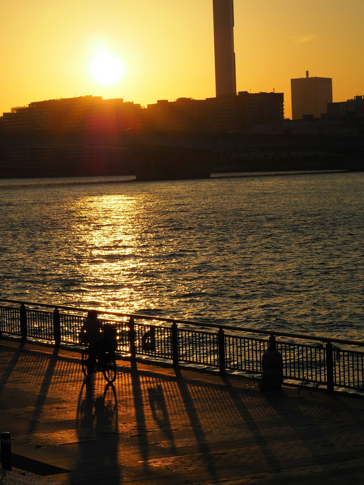 夕日が沈む川辺でシルエットの人々と影が映る