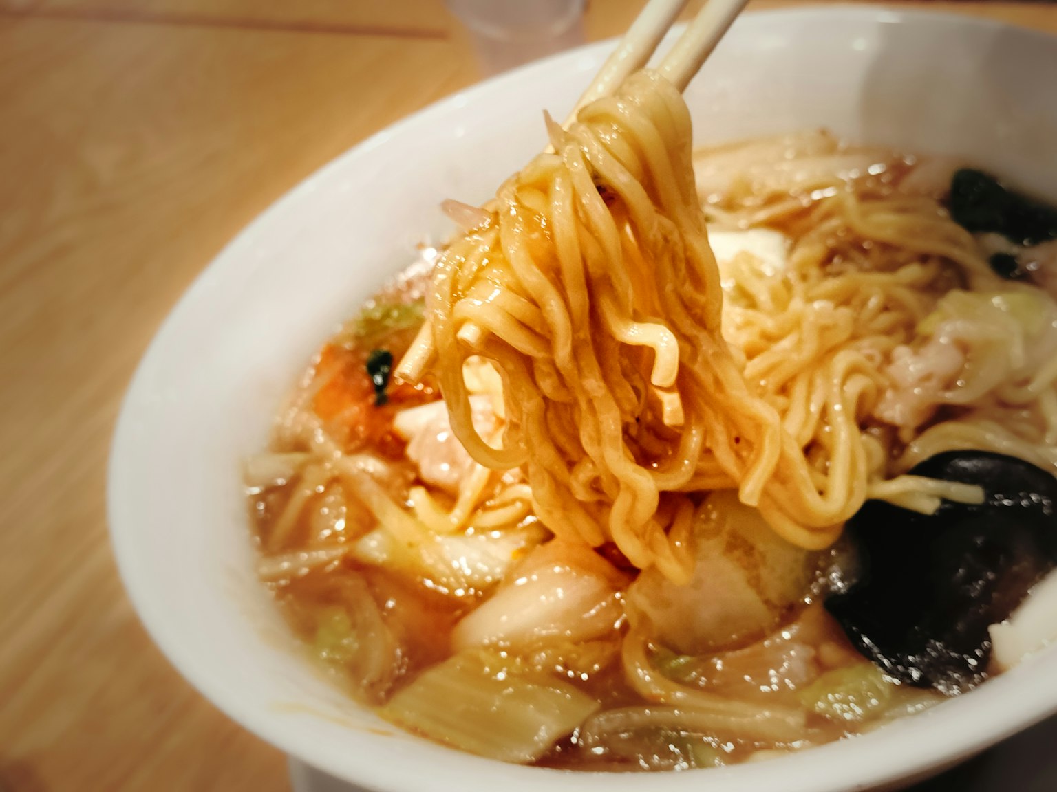 Mangkuk ramen dengan mie diangkat dengan sumpit