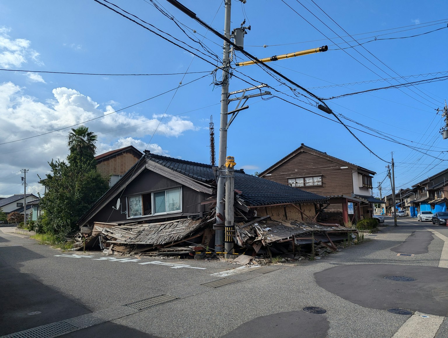 Blick auf ein beschädigtes Haus an einer Kreuzung mit einem Strommast