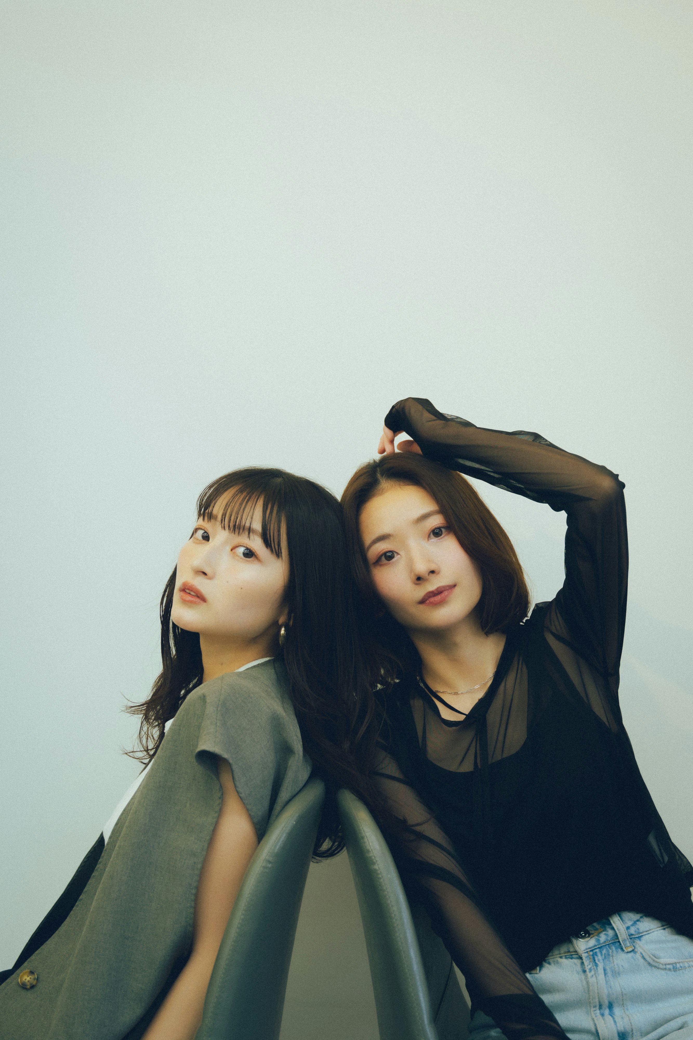 Two women posing closely in front of a plain background