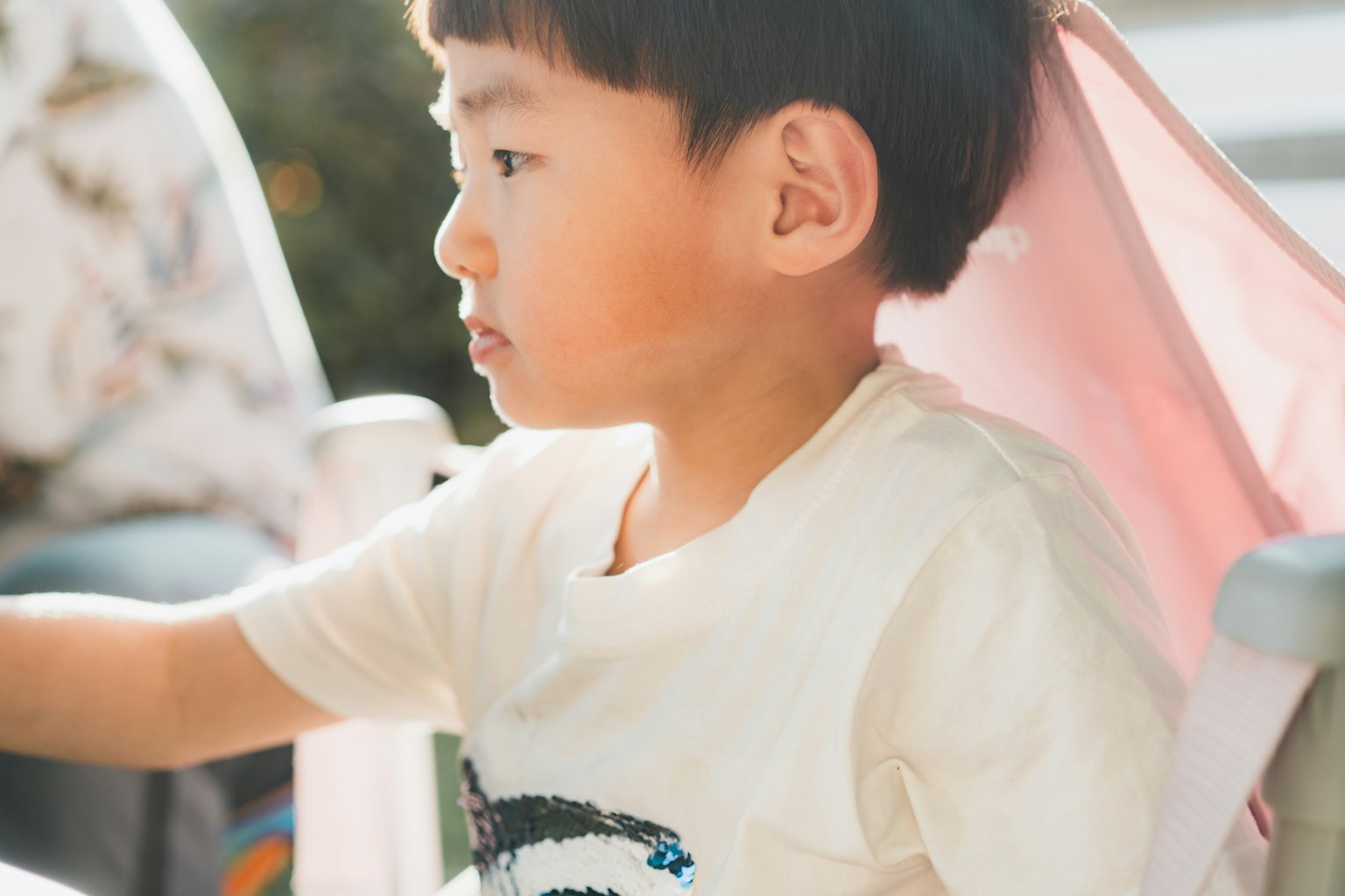 부드러운 조명과 밝은 색상의 의자에 앉아 있는 아이의 측면 사진