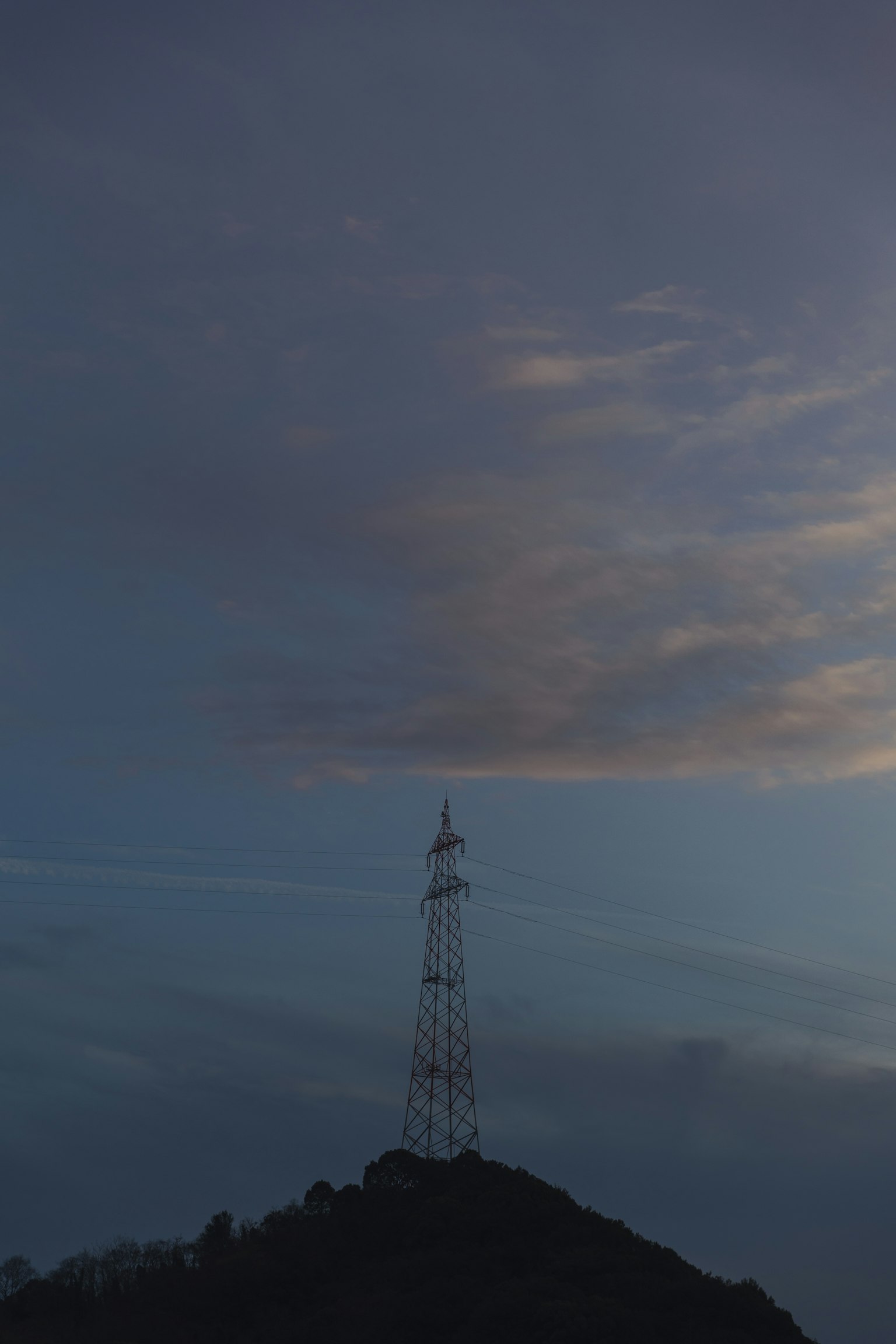 Communication tower on a hill under a darkening sky