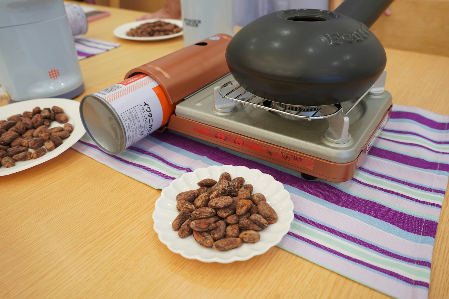Table avec une machine à rôtir et une assiette de fèves de cacao