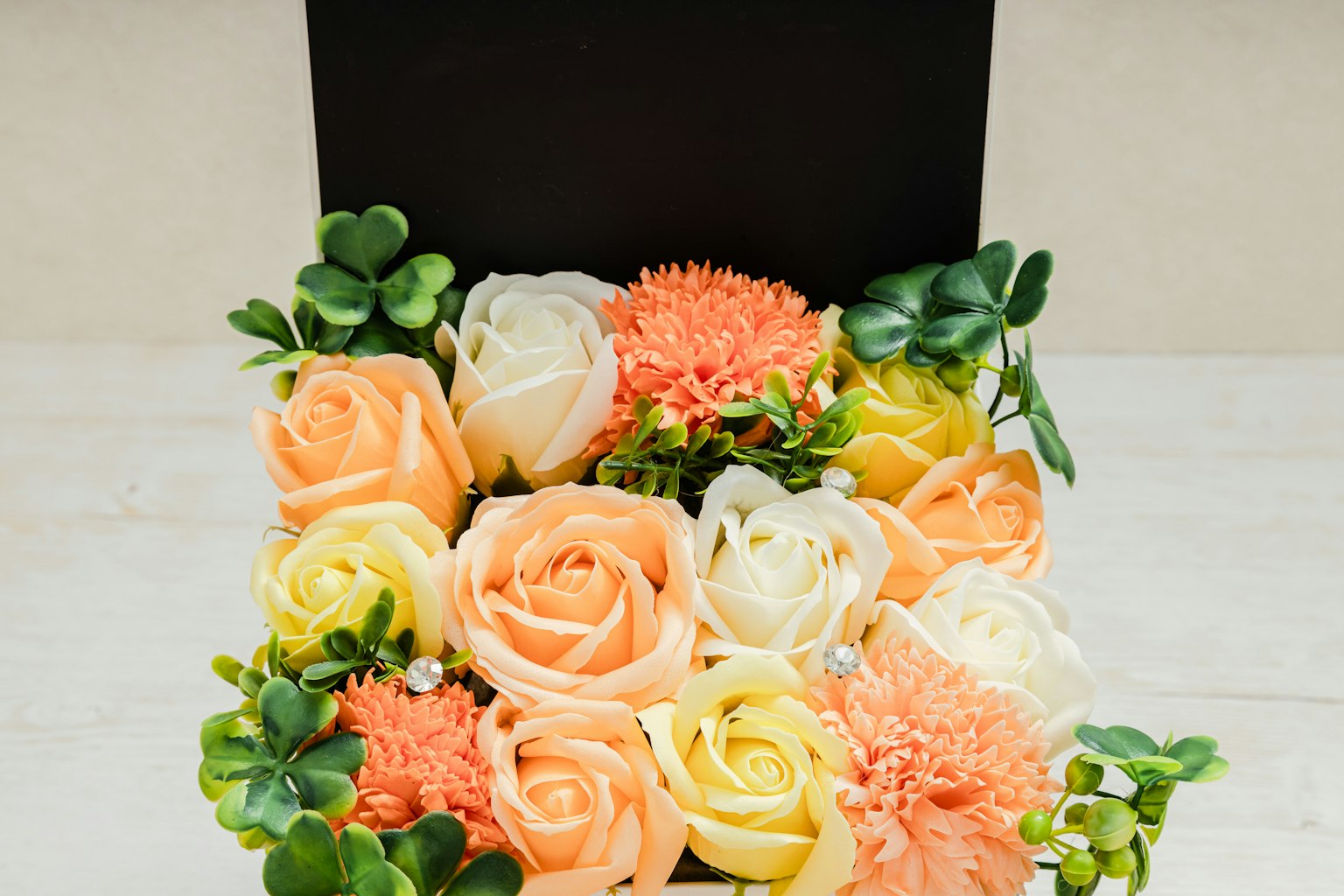 Box-Arrangement mit orangefarbenen und weißen Rosen sowie grünen Blättern