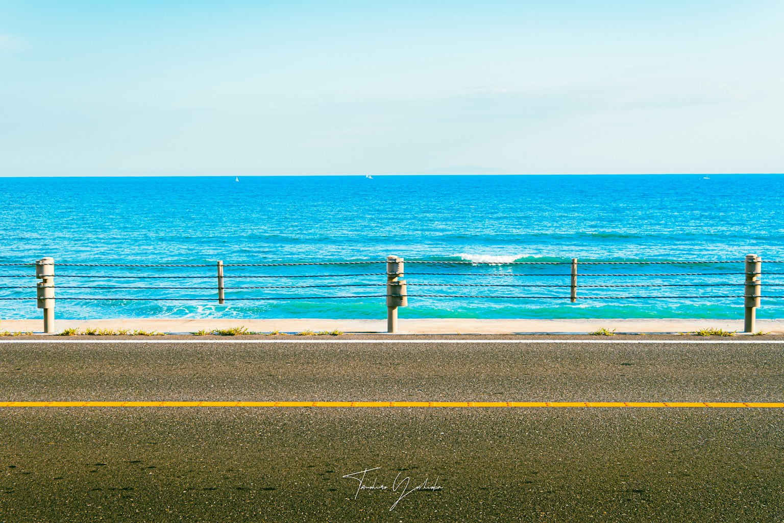 Vue panoramique d'un océan bleu avec des vagues douces à côté d'une route