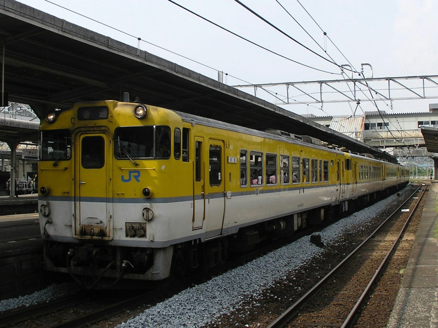 Kereta JR kuning berhenti di stasiun