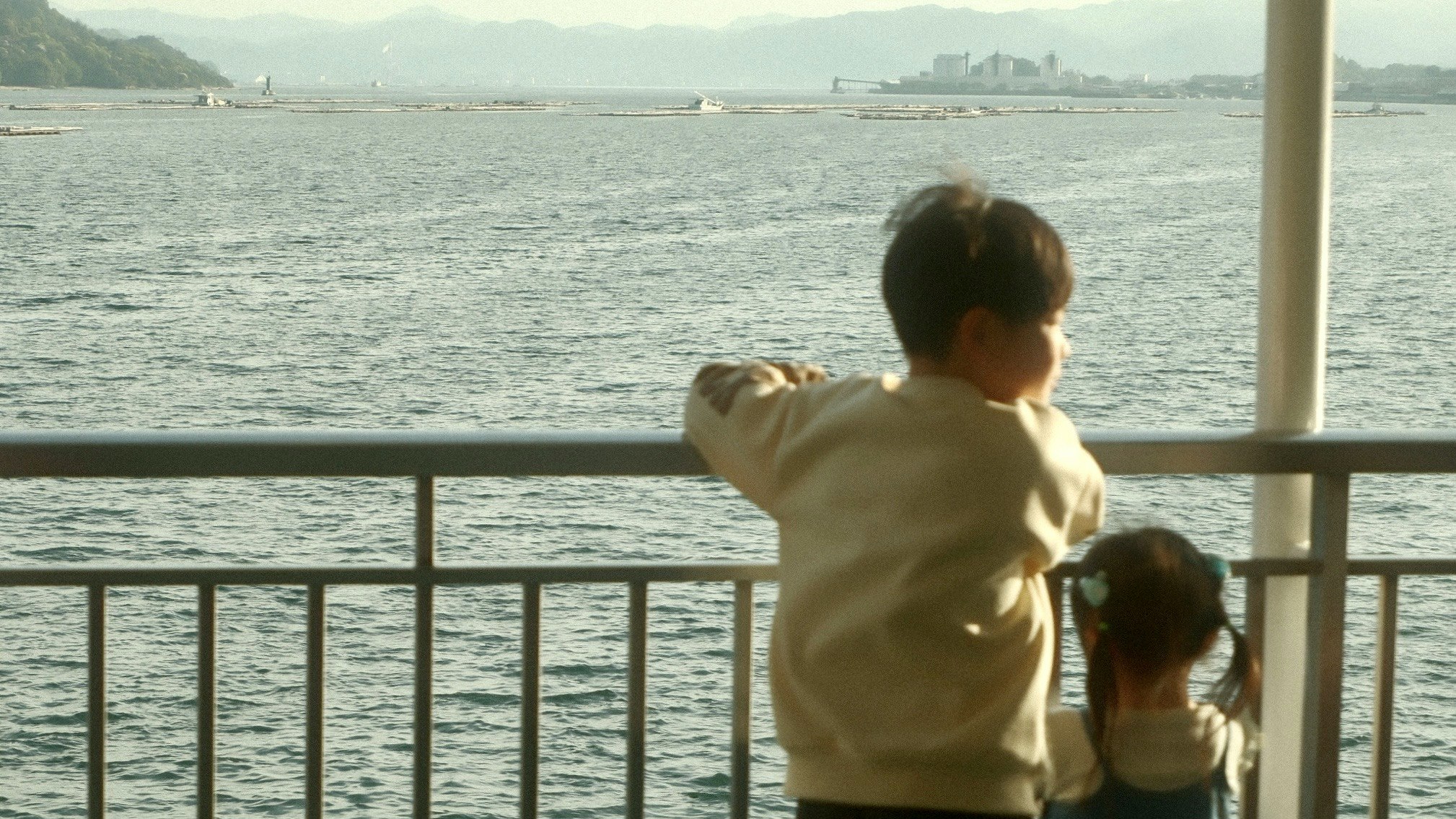 海を見つめる親子の後ろ姿が窓越しに広がる景色