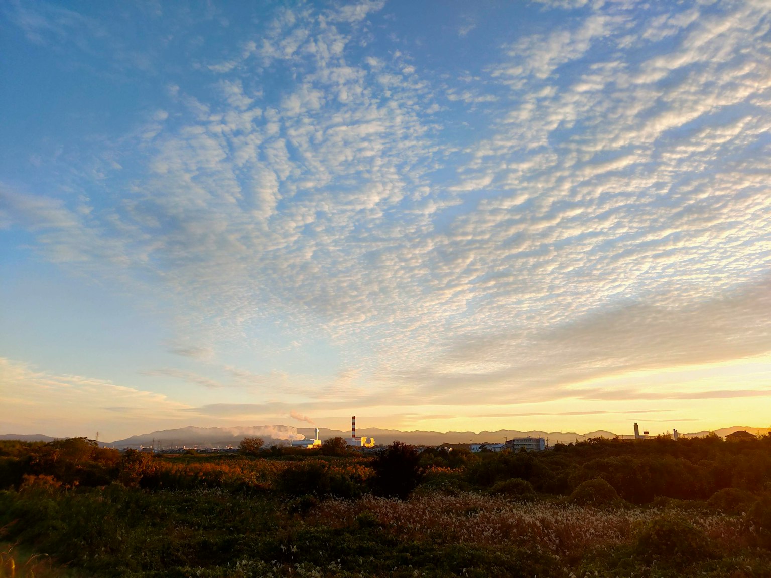 Paisaje con cielo azul y nubes con siluetas industriales