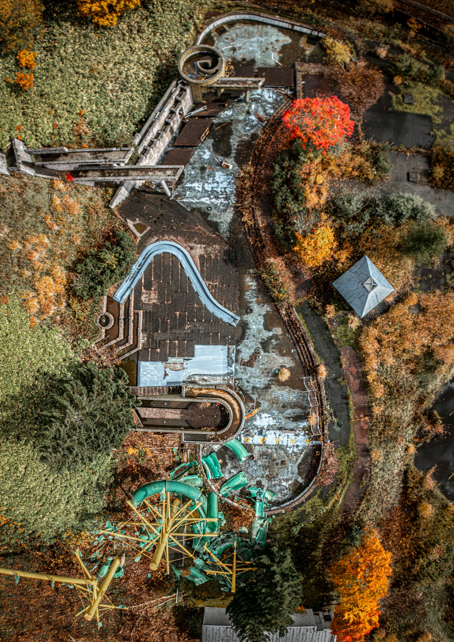廃墟の遊園地の上空写真 色とりどりの木々と水滑り台が見える