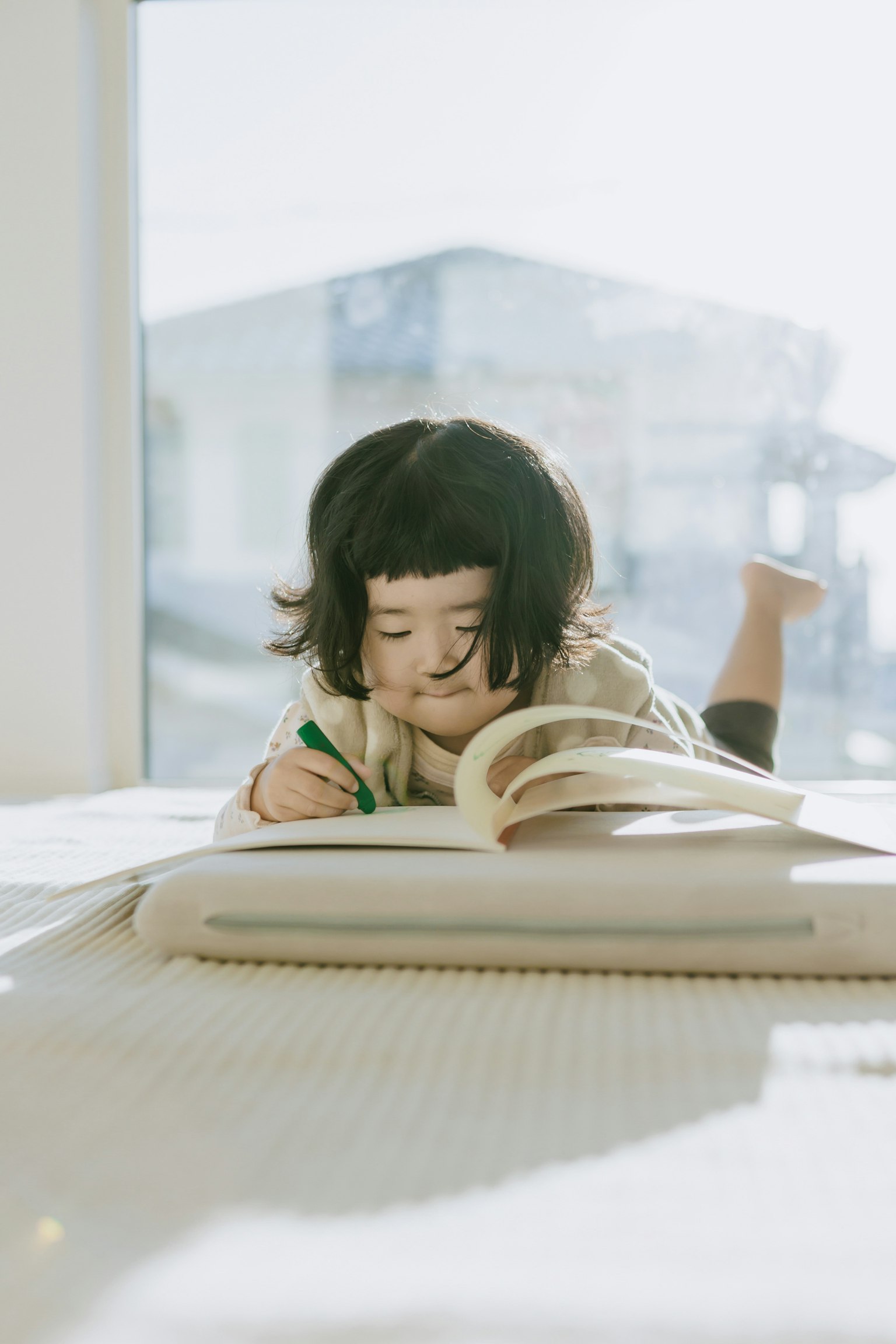 子供が本に夢中になっている様子 窓からの自然光が差し込む部屋で