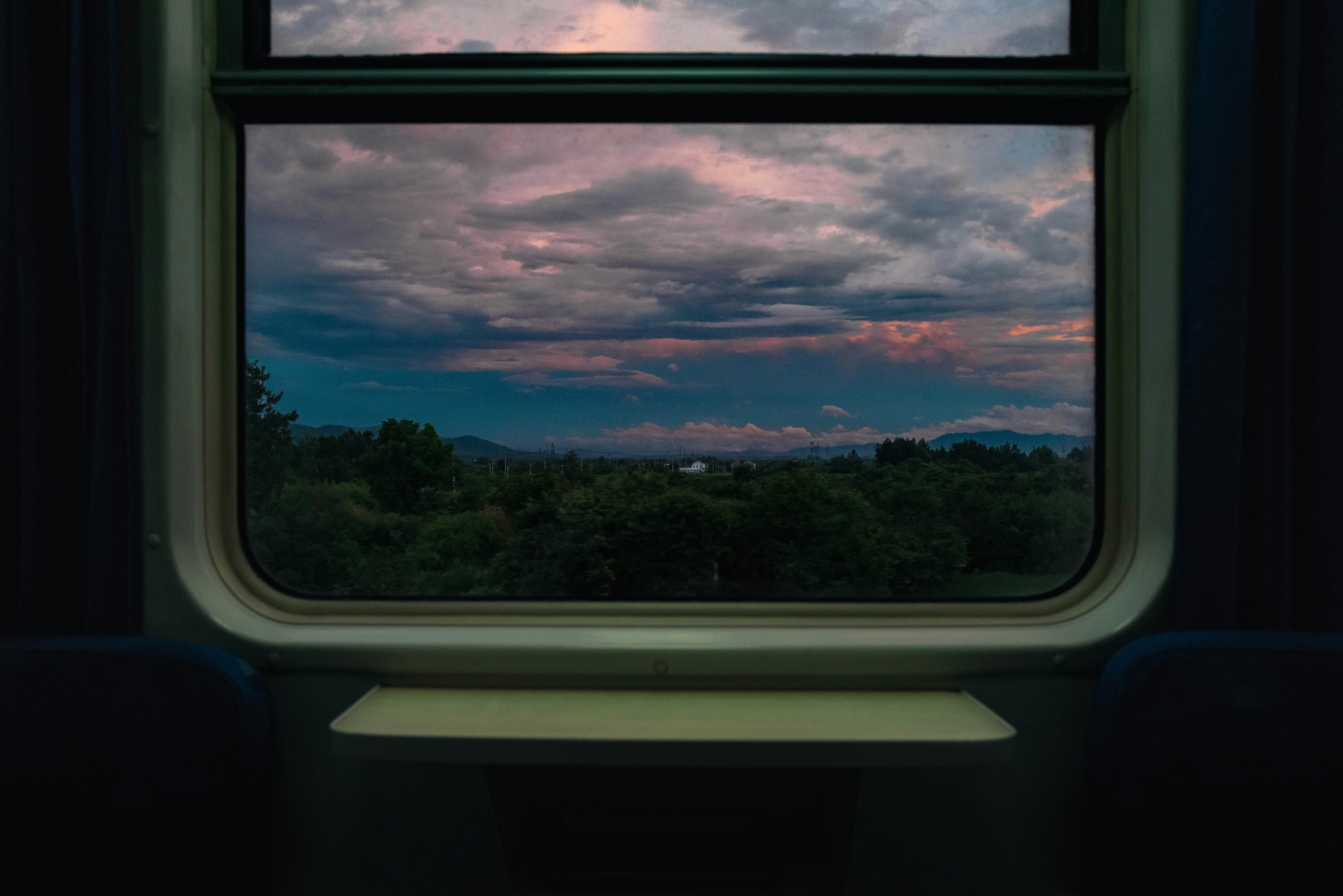 窓から見える夕焼けの空と森の景色