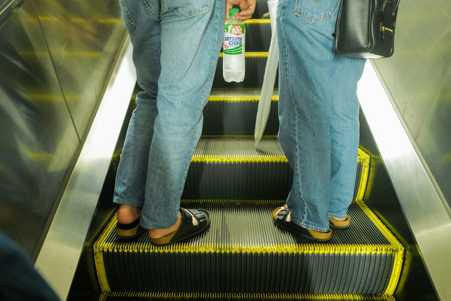Deux paires de pieds sur un escalator avec des jeans