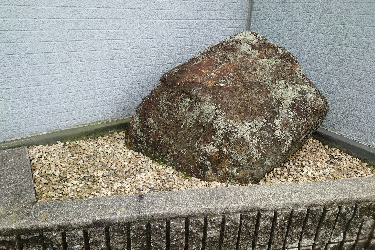 Una gran roca colocada sobre pequeñas piedras en un jardín sencillo