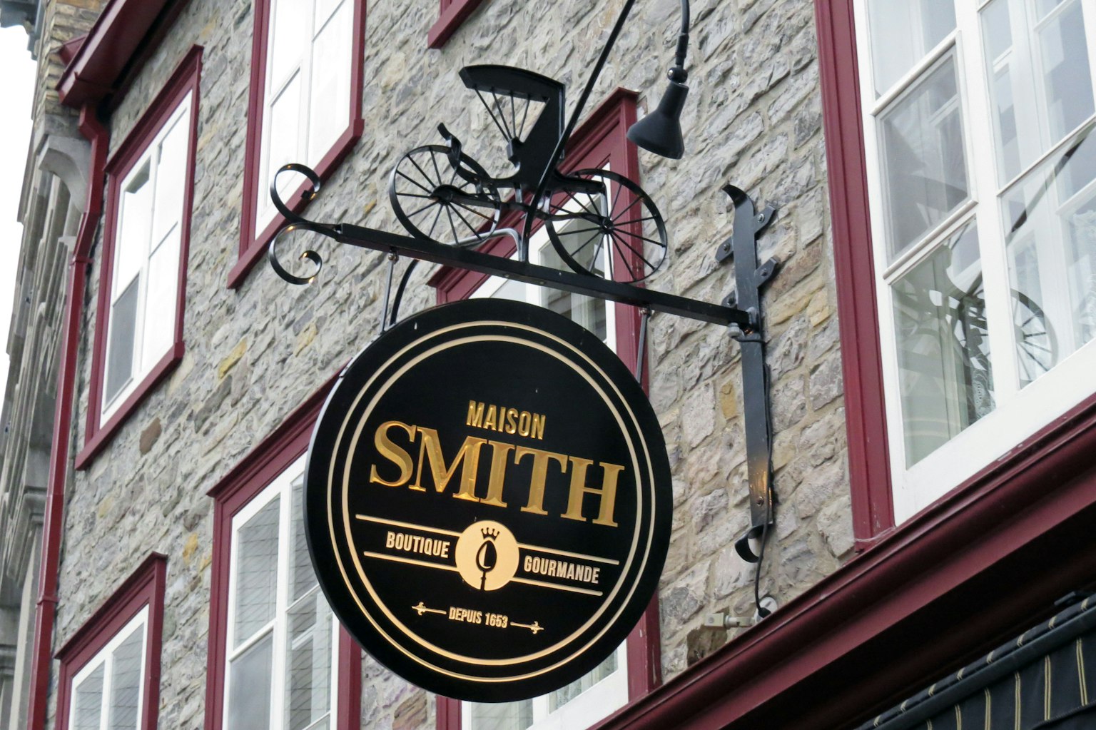 Papan hitam dan emas yang tergantung dari bangunan batu dengan nama Marson Smith