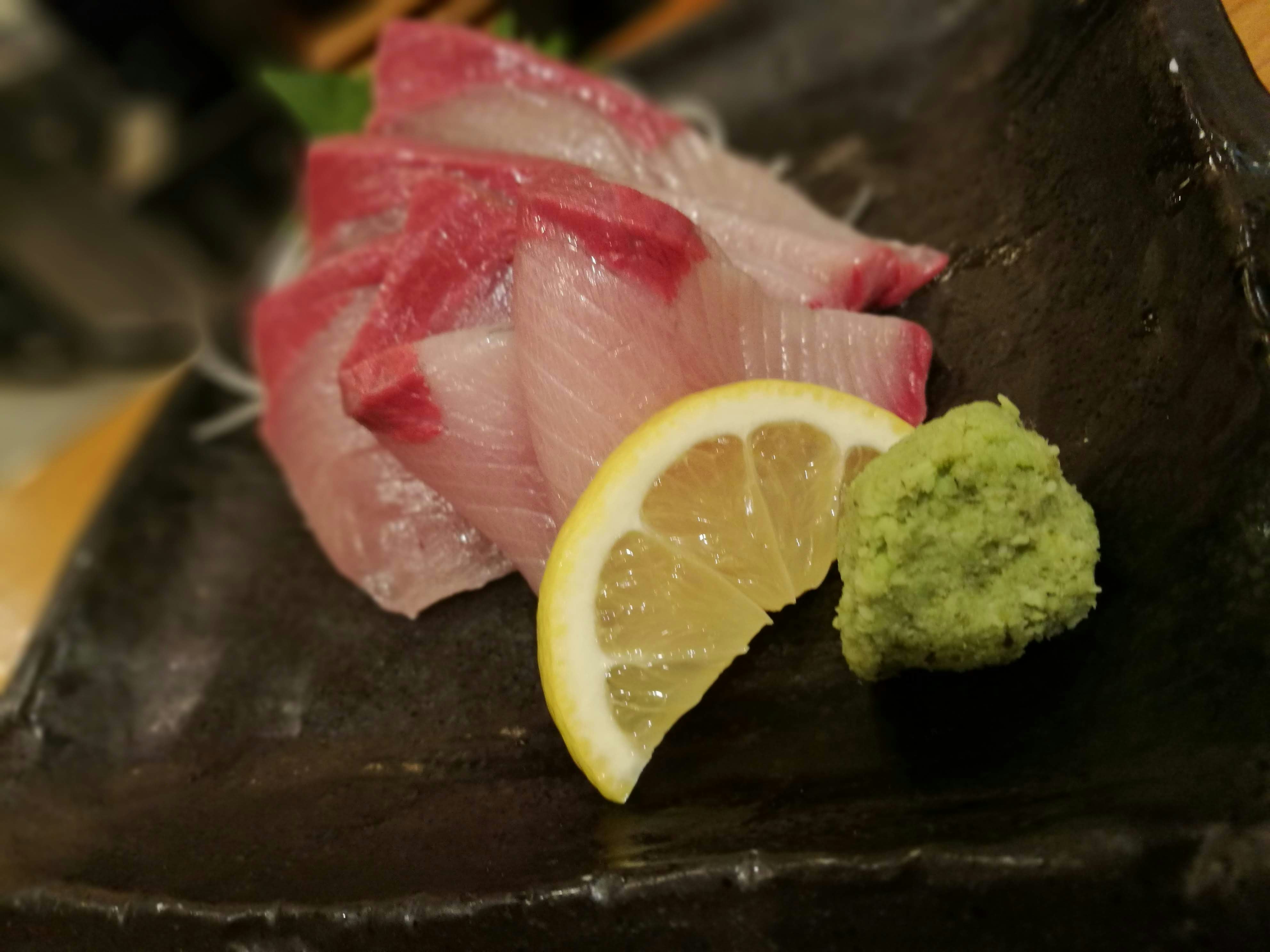 深色盤中的生魚片配檸檬和芥末