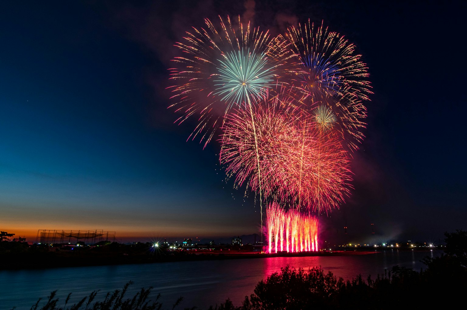 Fuochi d'artificio colorati che esplodono nel cielo notturno sopra un fiume