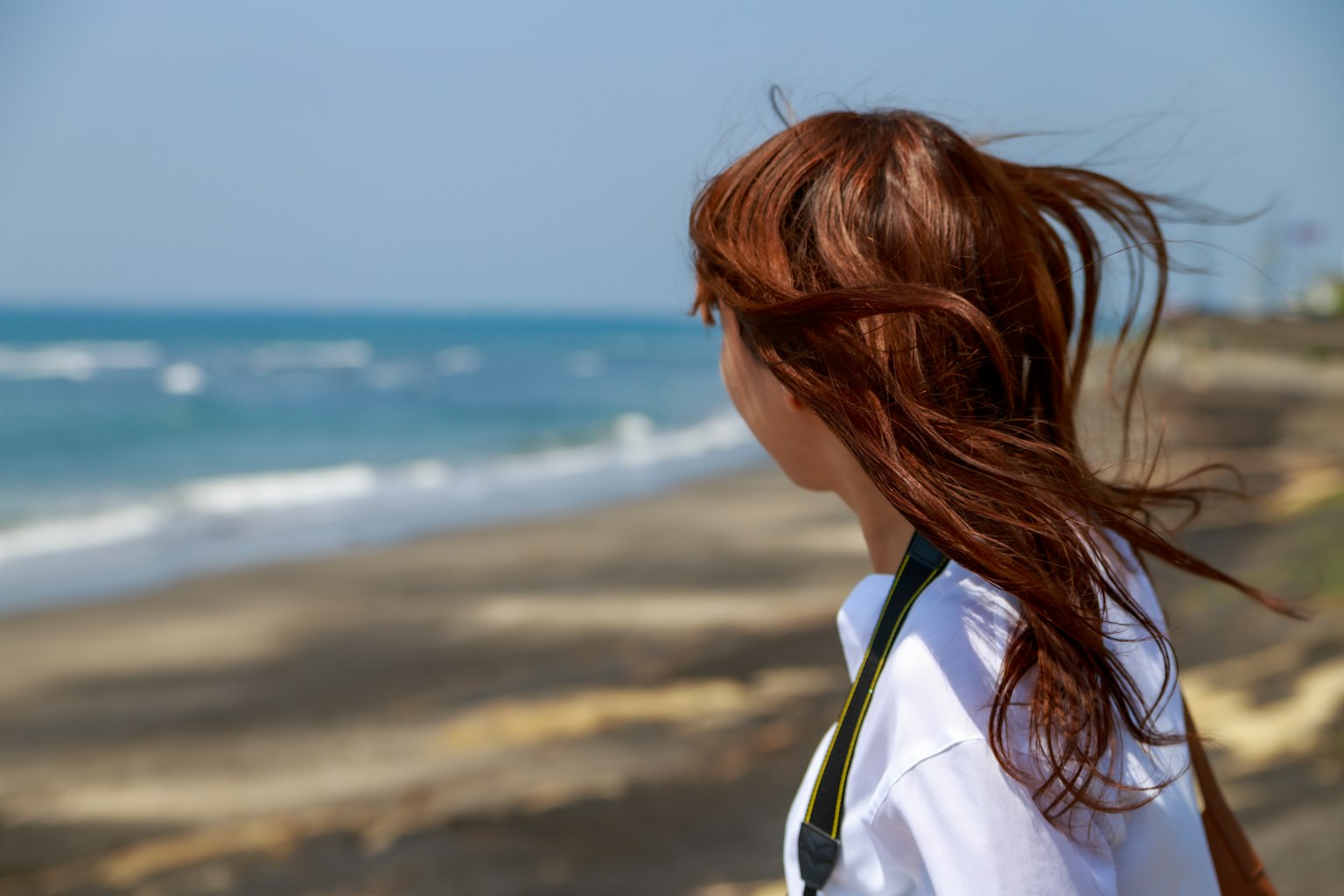 女性凝視海洋,頭髮在風中飄動