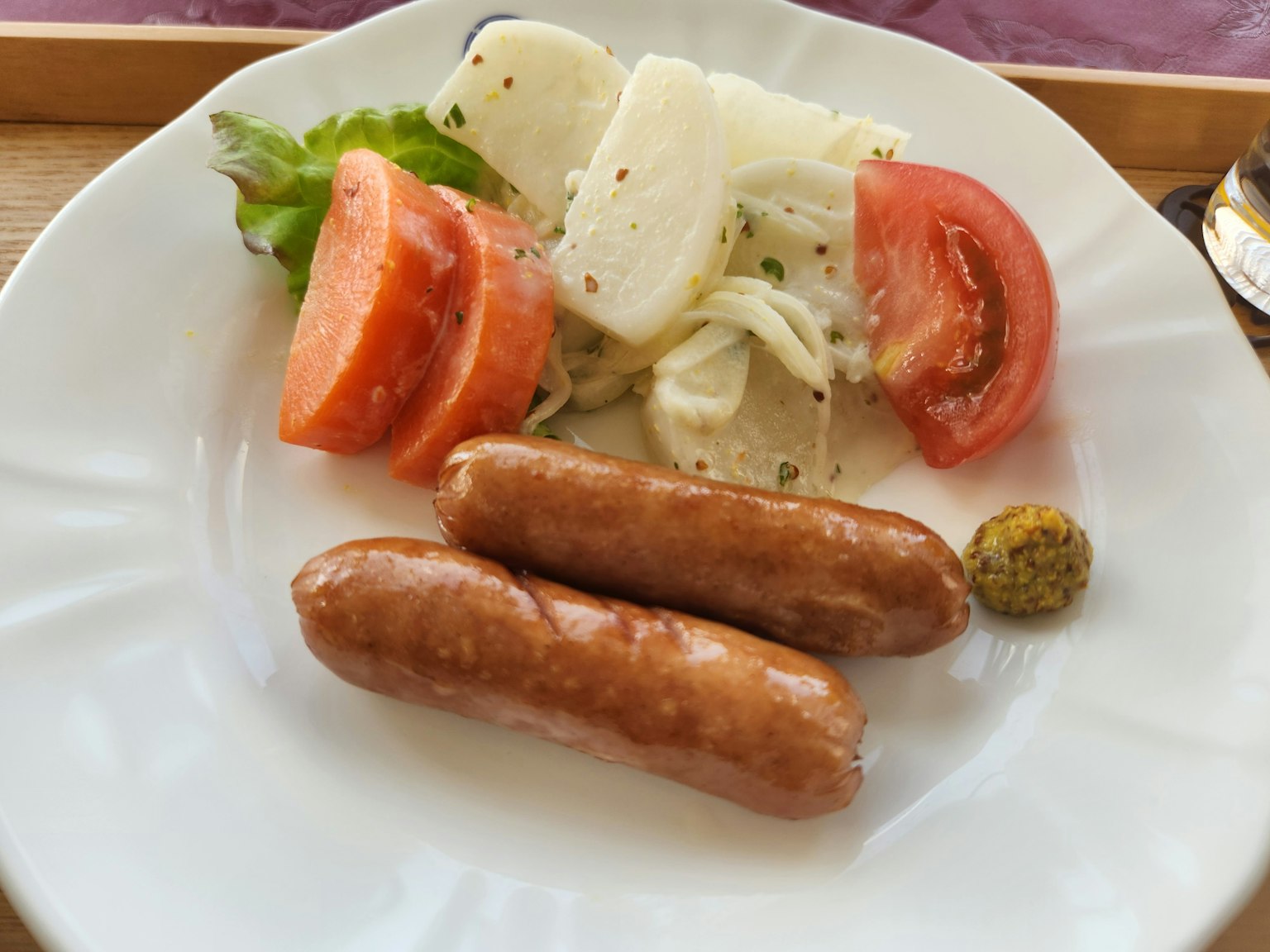 Piring dengan sosis dan salad segar termasuk tomat dan selada