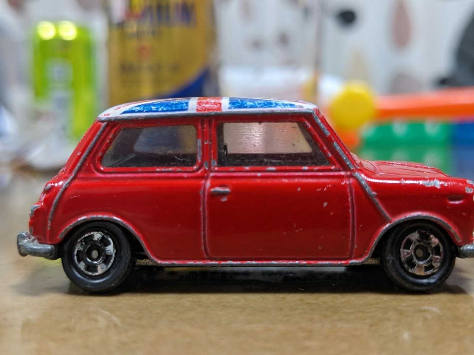 Vue latérale d'une voiture jouet rouge avec un toit bleu et blanc