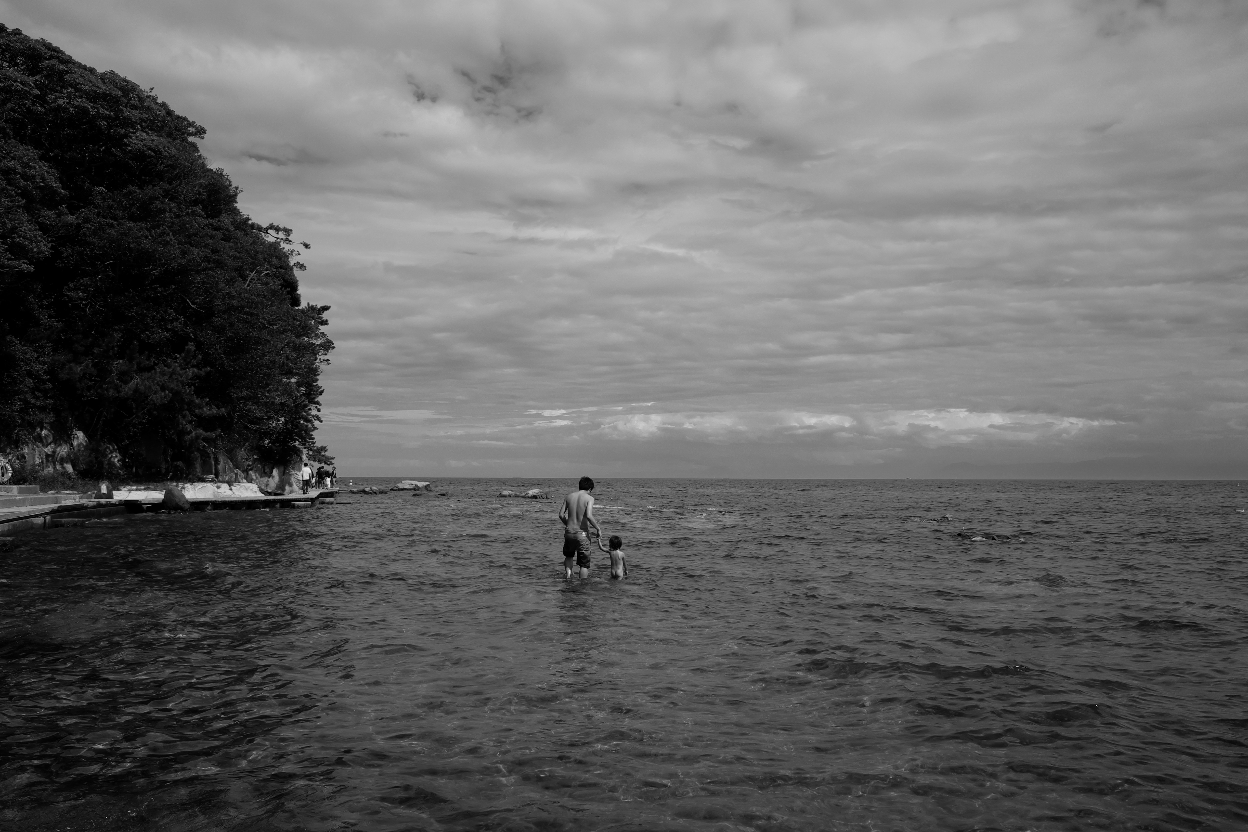 能登の海辺を歩く人と曇天の水平線